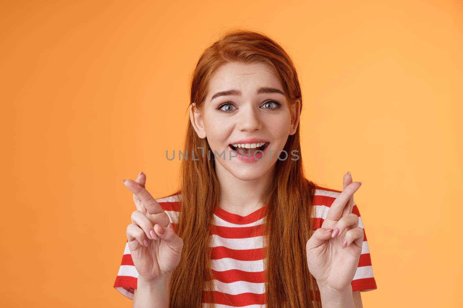 Excited hopeful redhead girl hope win lottery, smiling optimistic, look faith, believe dream come true, cross fingers good luck, make wish, anticipate good news, praying fortune, orange background.