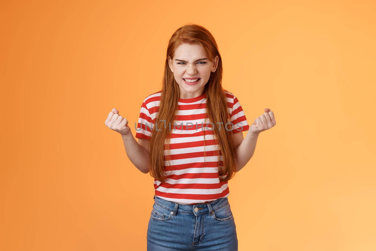 Annoyed pissed redhead female lose competition, clench fists angry grimacing evil hateful face, pressured, hate unfair results, stand orange background bothered, depressed and irritated.