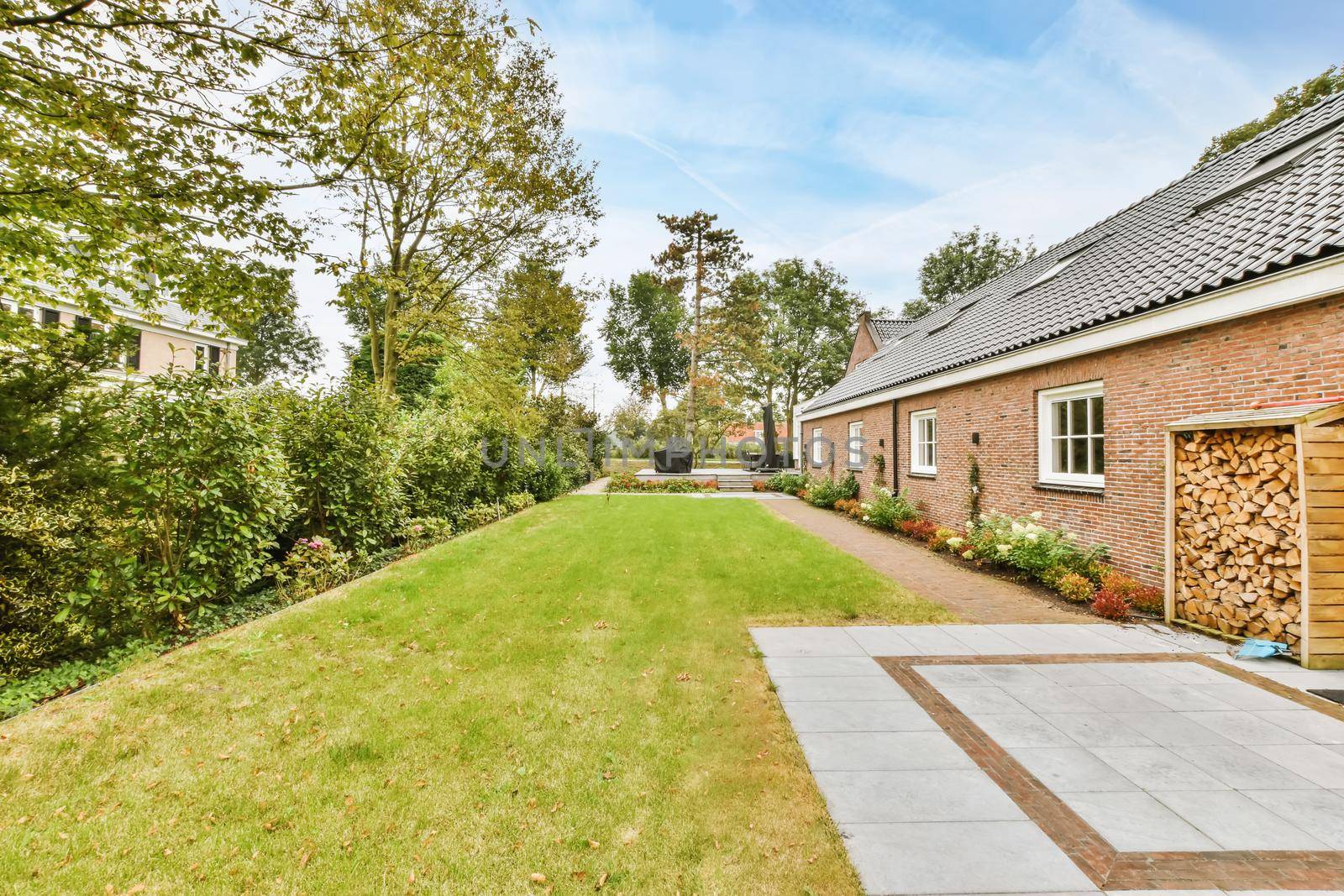 The facade of a one-story brick house with a green fresh lawn in front of the house