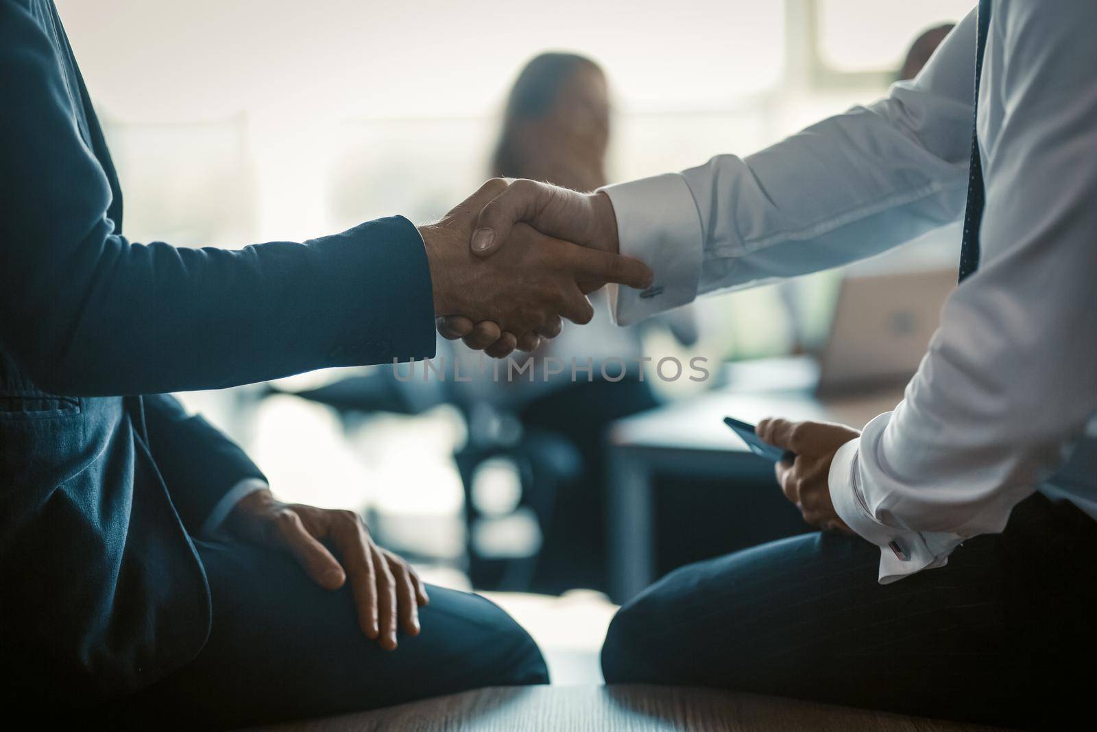 Handshaking of two business persons colleagues on modern office background. Business concept. Close up shot.