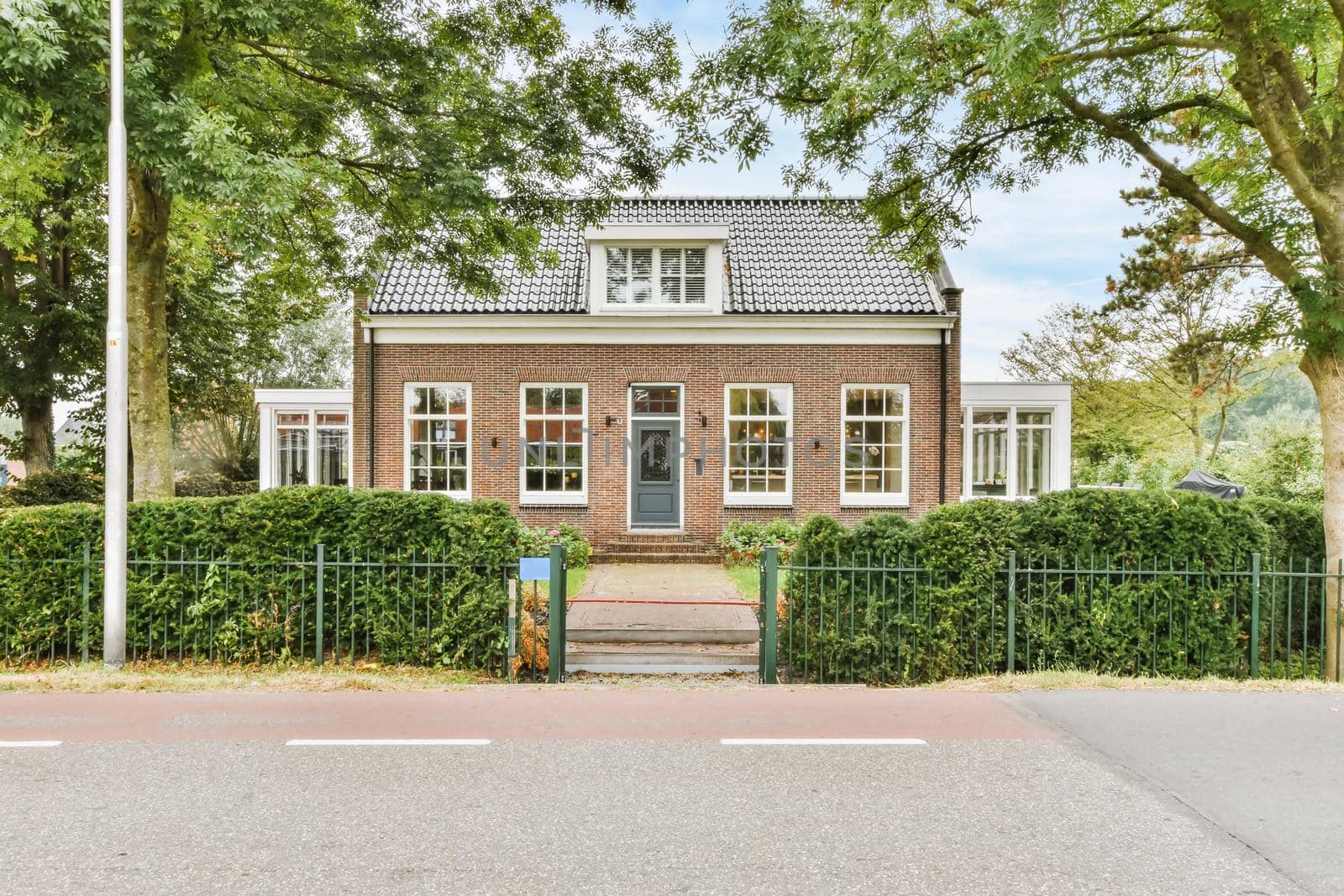 View of an on-storey brick house with greenery on the street