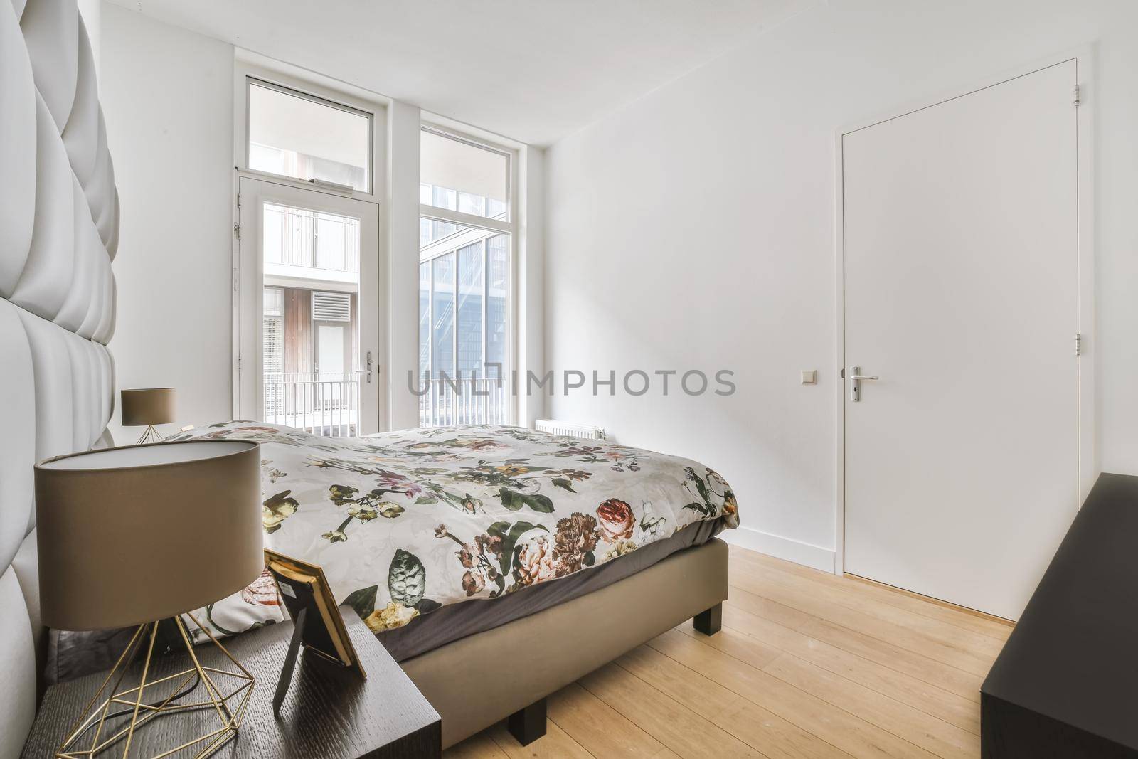 Minimalist interior design of small bedroom with soft bed placed in corner and wooden wardrobe and shelves with lamp illumination