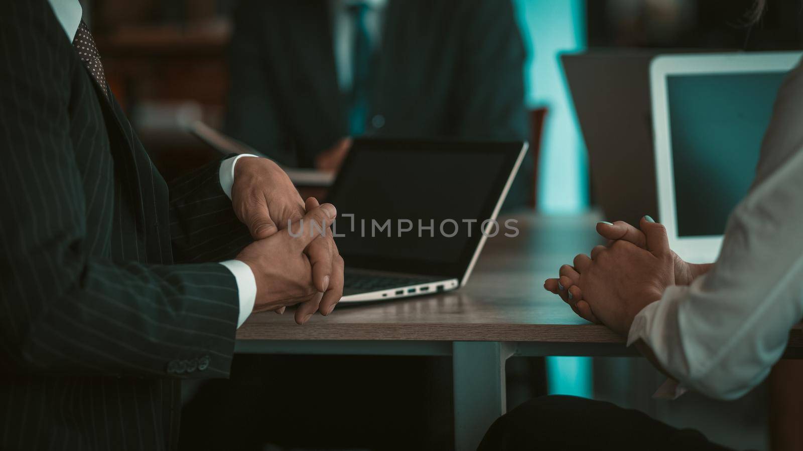 Two adult business people having a conversation sitting at the table with laptop computers in an office at desk, working in the company's office for software development by LipikStockMedia