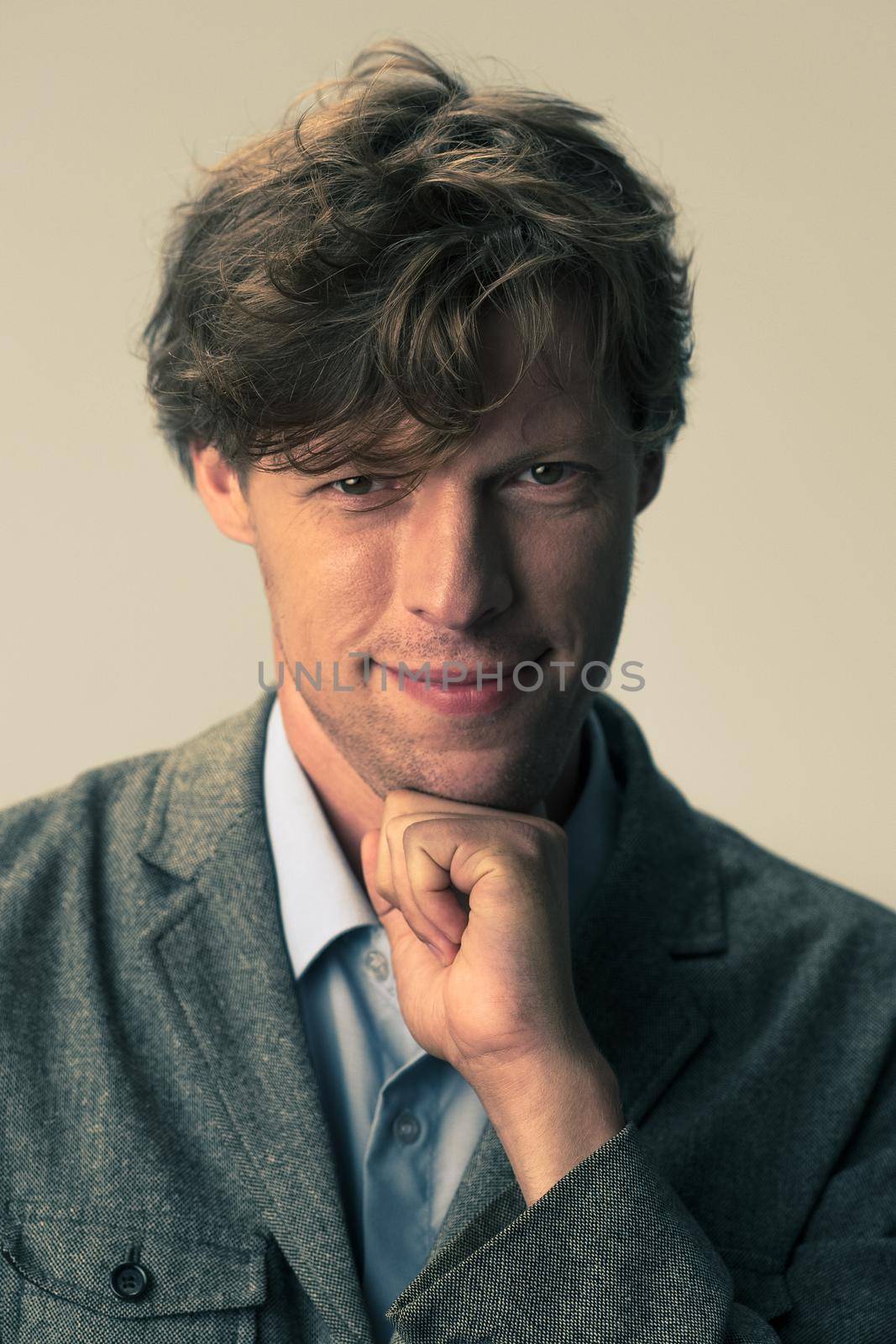 Business man in a suit with his leaned chin on a fist. Handsome confident caucasian standing with crossed arms isolated on white background. Tinted image by LipikStockMedia