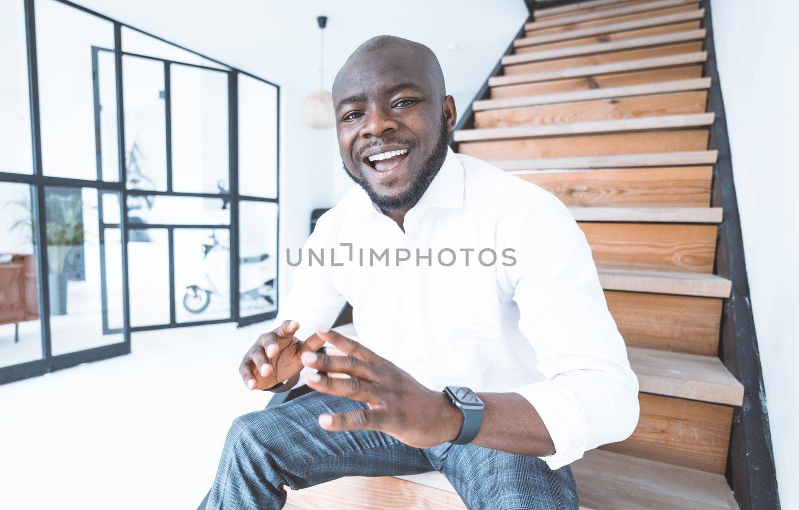 Successful Handsome Man in White Shirt Sits on the Steps in His Mansion. Nice Guy with a Big Smile. Close-up Portrait. High quality photo