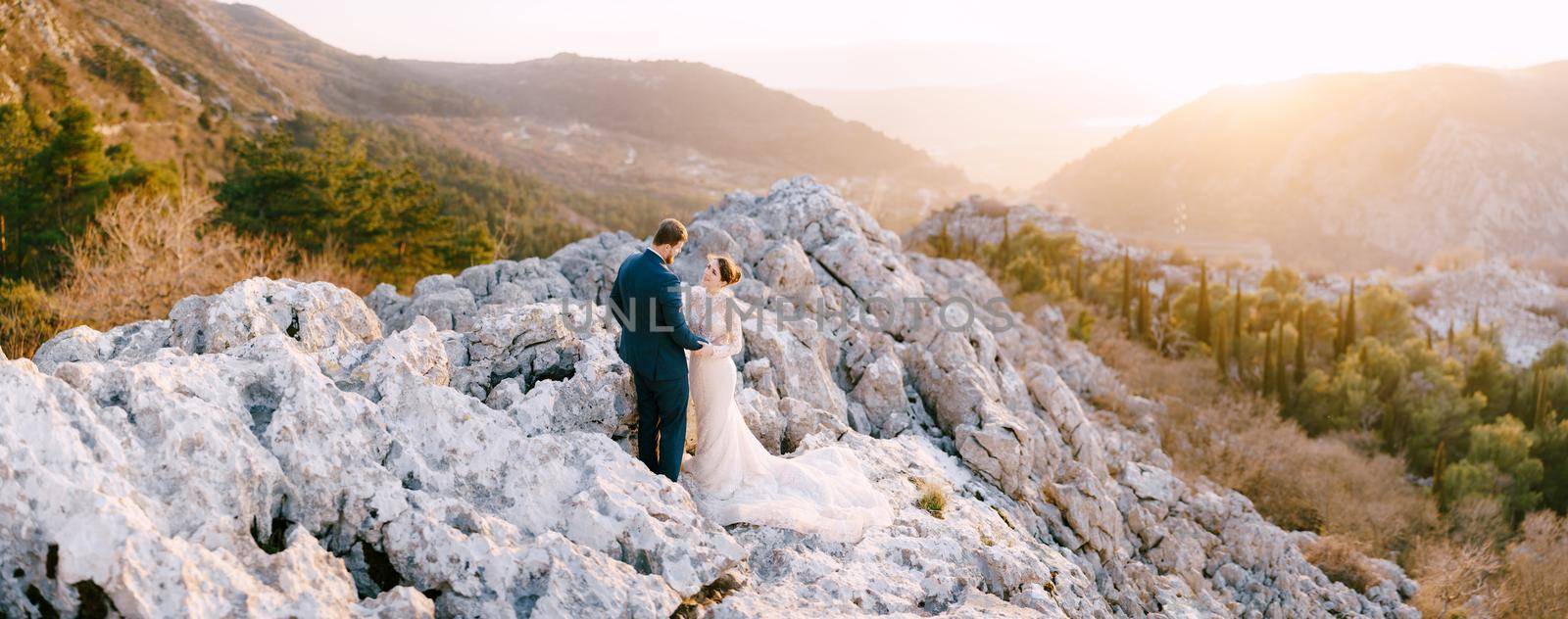 Bride and groom hug on the rocks against the background of mountains. High quality photo