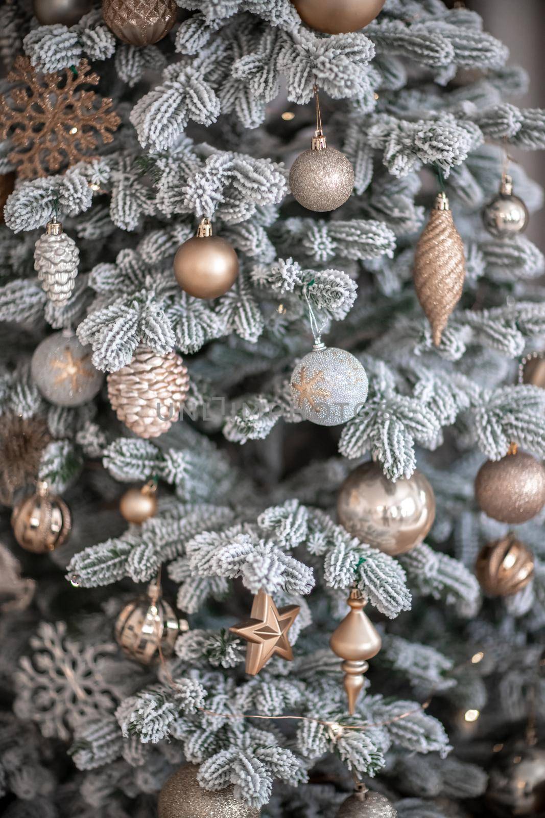 Close-up of a festively decorated outdoor Christmas tree with balls on a blurred sparkling fairy background. Defocused garland lights, bokeh effect. by Matiunina