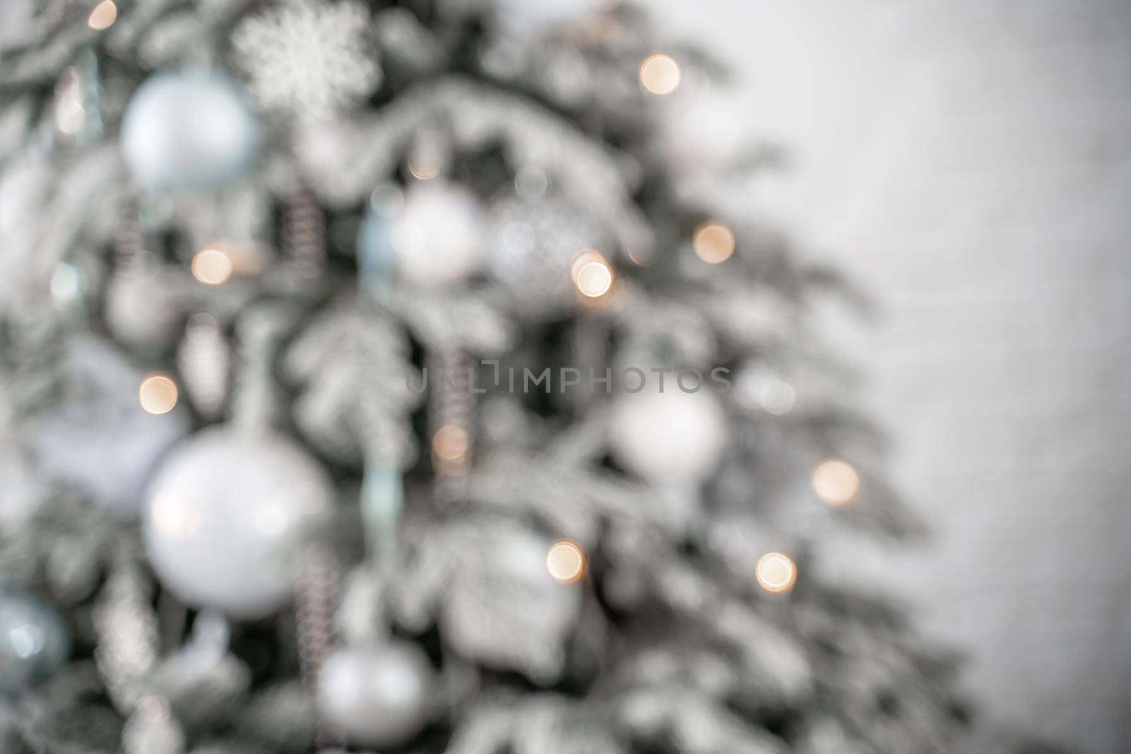 Close-up of a festively decorated outdoor Christmas tree with balls on a blurred sparkling fairy background. Defocused garland lights, bokeh effect