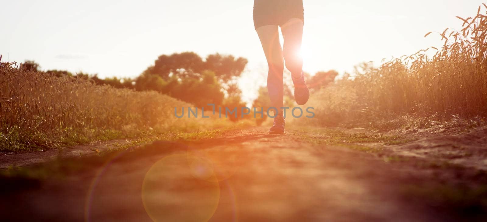 Young sports girl in a top and shorts trains outdoors, runs at sunset. A woman is engaged in trail running outdoor, preparing for a long race.