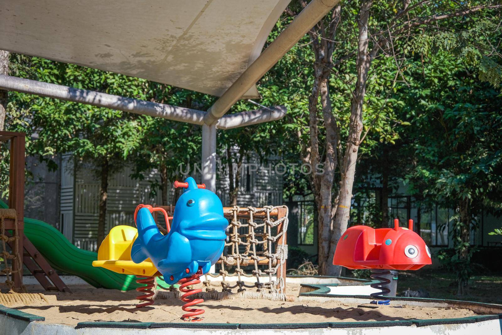 Colorful playground on yard in the park. Rocking horse and climbing rope for children in public park. by TEERASAK