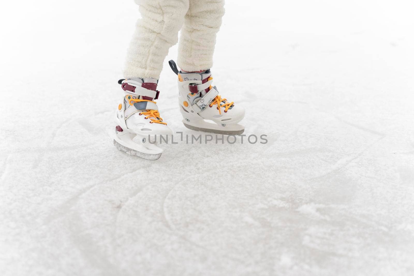 child is skating on the rink, legs close-up and place for text