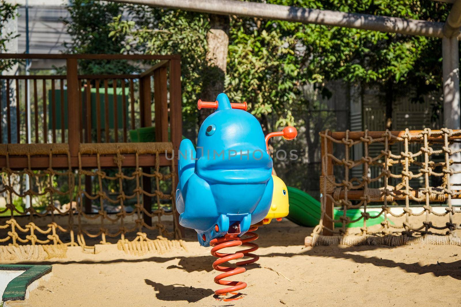 Colorful playground on yard in the park. Rocking horse and climbing rope for children in public park.