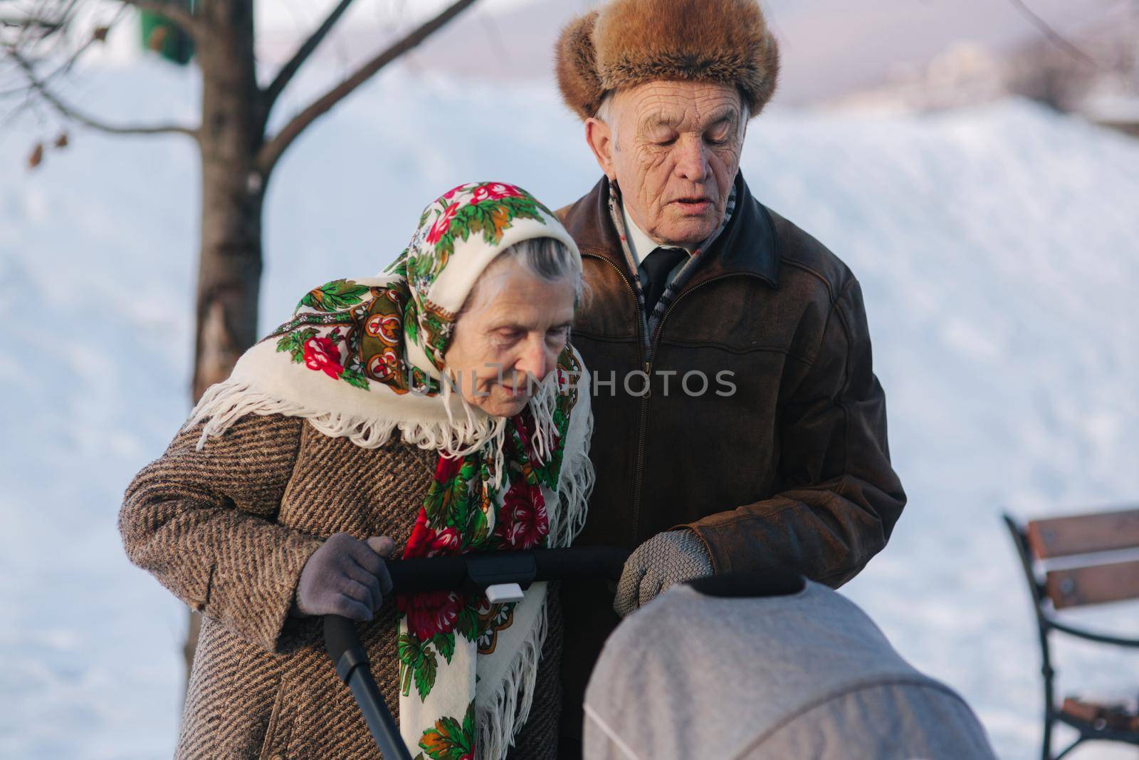 Grand Grandparents walking with a baby in beautiful pram. Winter time.