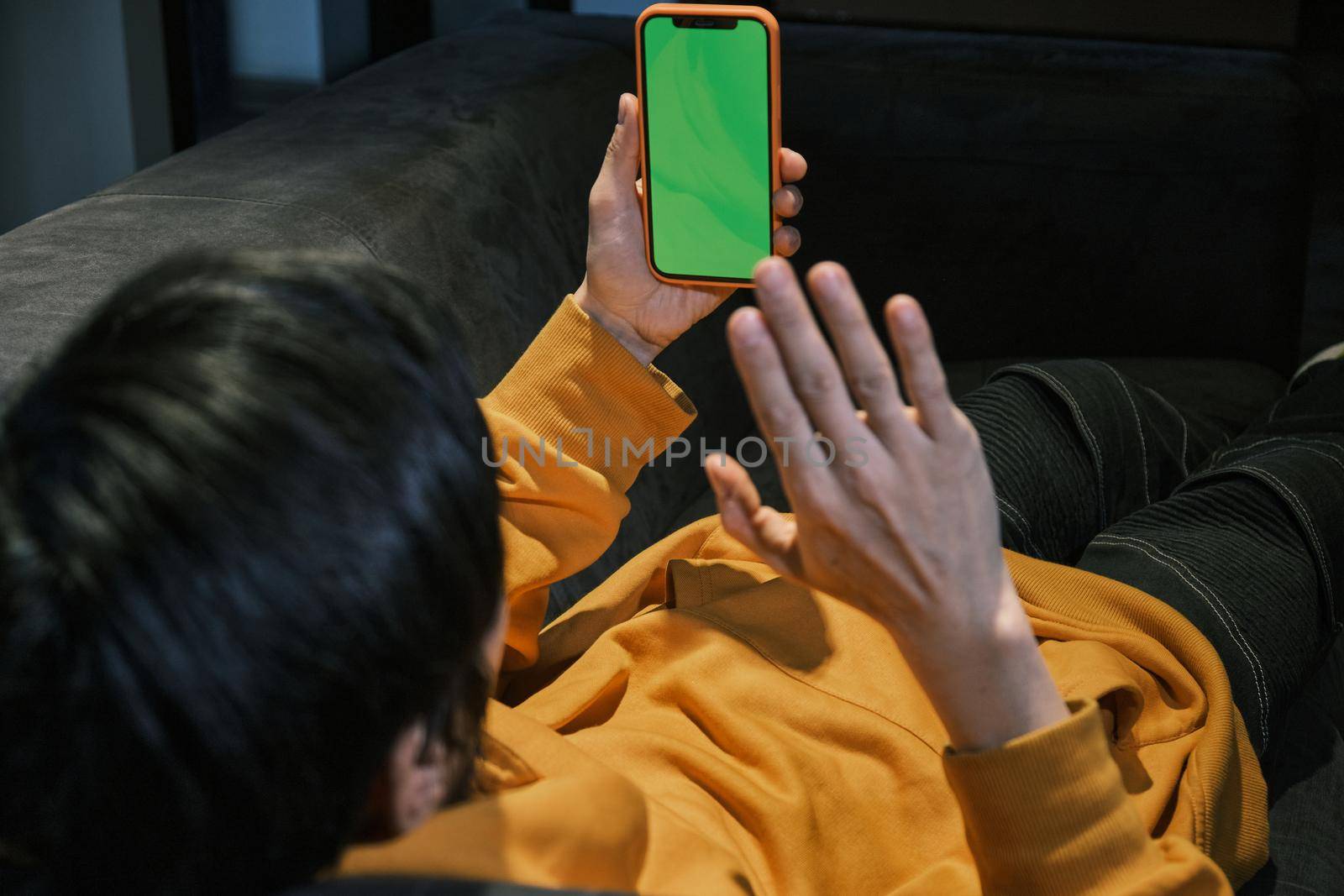 An Asian guy lays on sofa in office, communicates by mobile phone by snep_photo