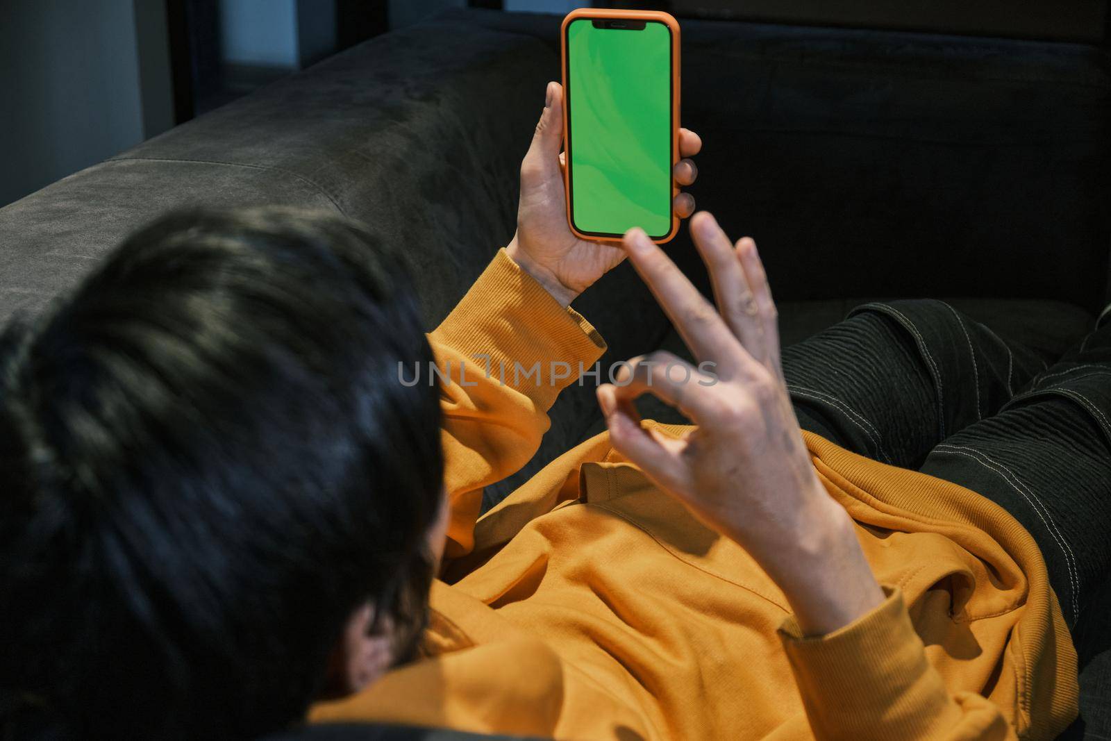 An Asian guy lays on sofa in office, communicates by mobile phone by snep_photo