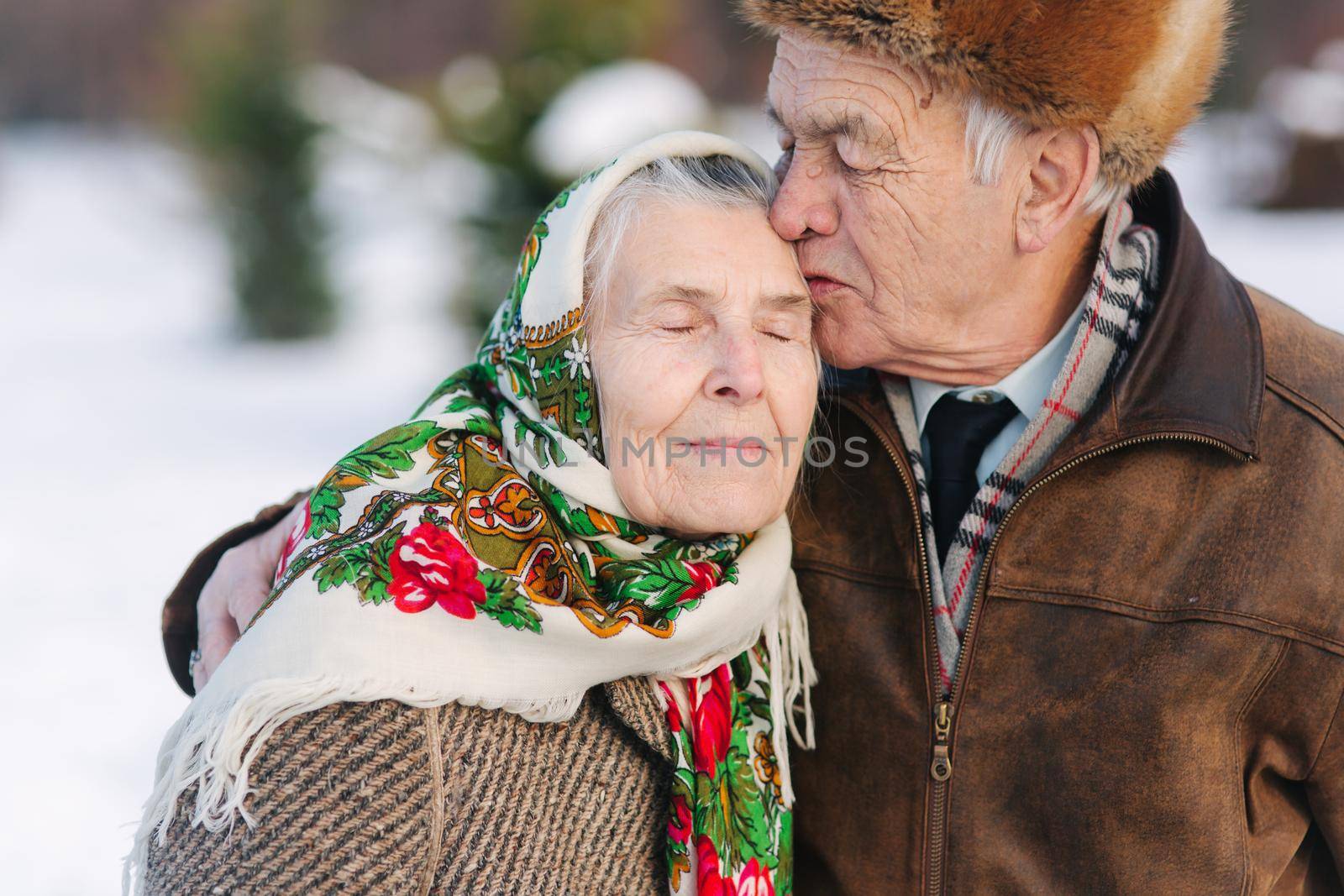 Portrait of senior couple. Elderly man kiss his wife in weighty. old couple walking in the park in winter time. Happy family. Gold wedding.