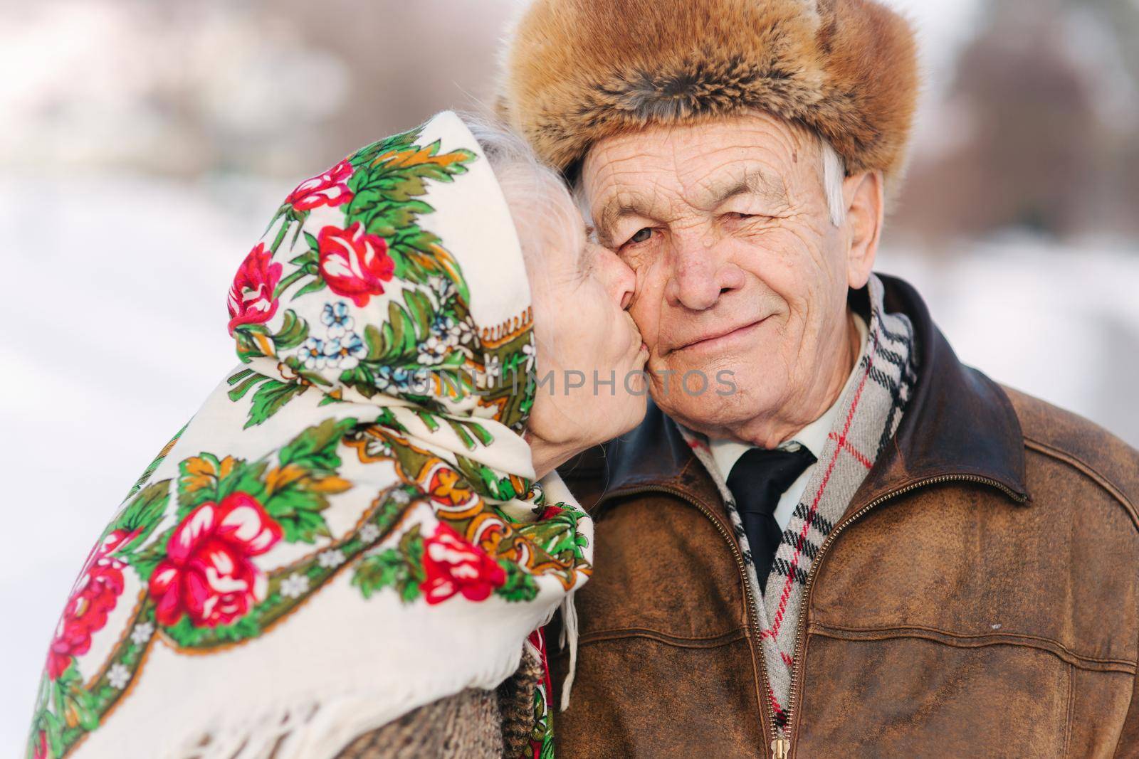 Portrait of happy senior couple. Elderly woman kiss her husband in weighty. old couple walking in the park in winter time. Happy family. Gold wedding by Gritsiv