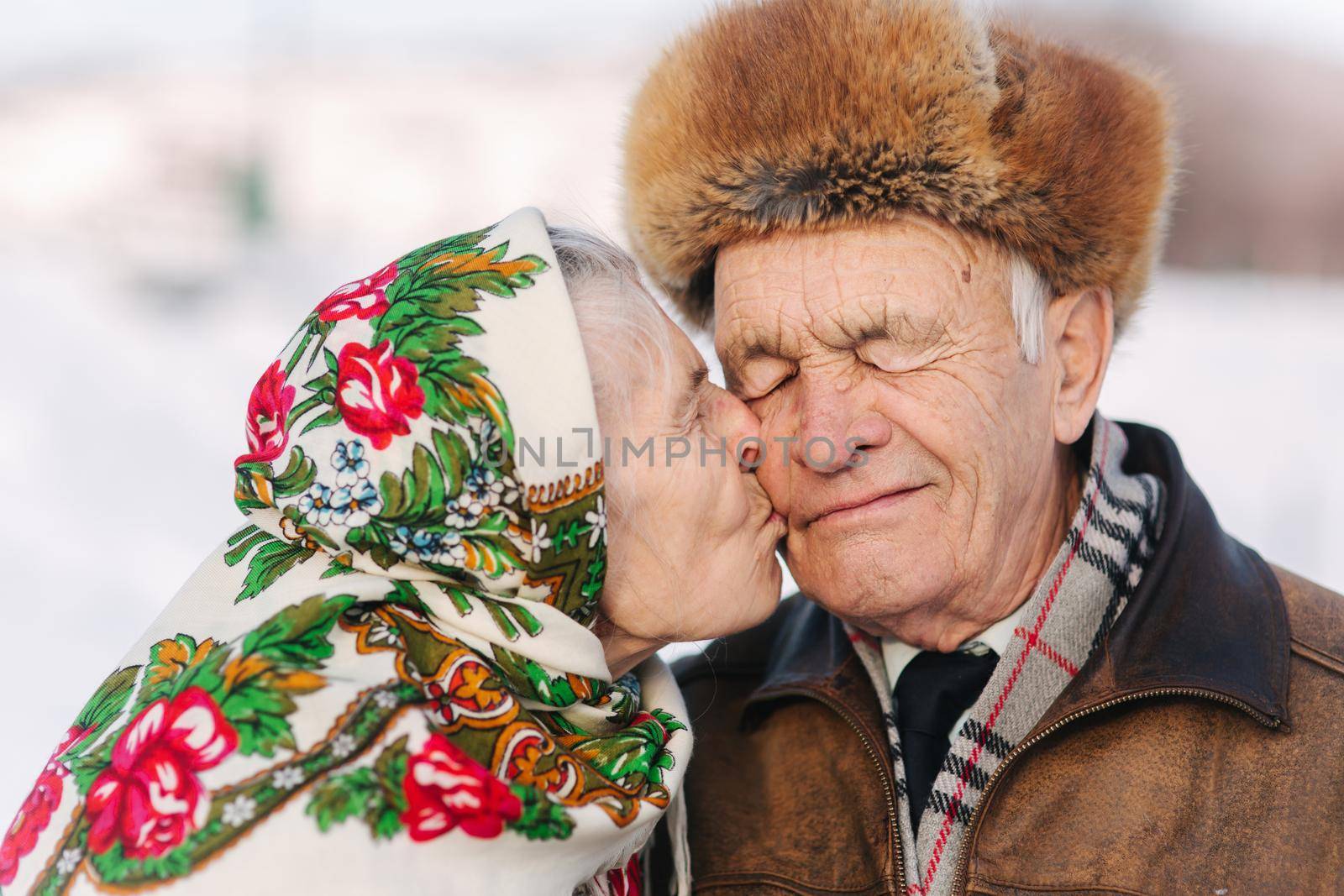 Portrait of happy senior couple. Elderly woman kiss her husband in weighty. old couple walking in the park in winter time. Happy family. Gold wedding by Gritsiv