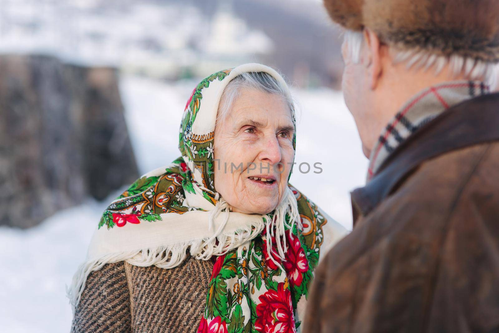 Senior people sitting on the bench in the park. Happy elderly couple spend time outside in winter by Gritsiv