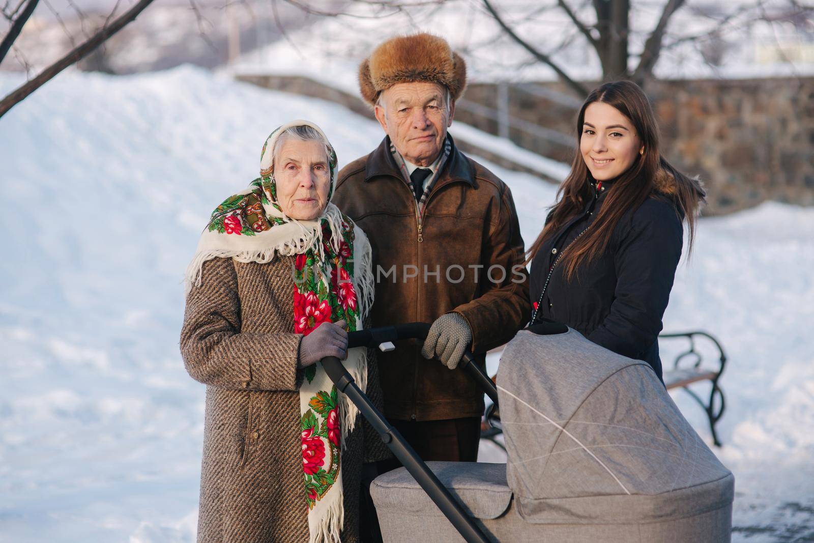 Grand Grandparents walking with a baby in beautiful pram. Winter time.