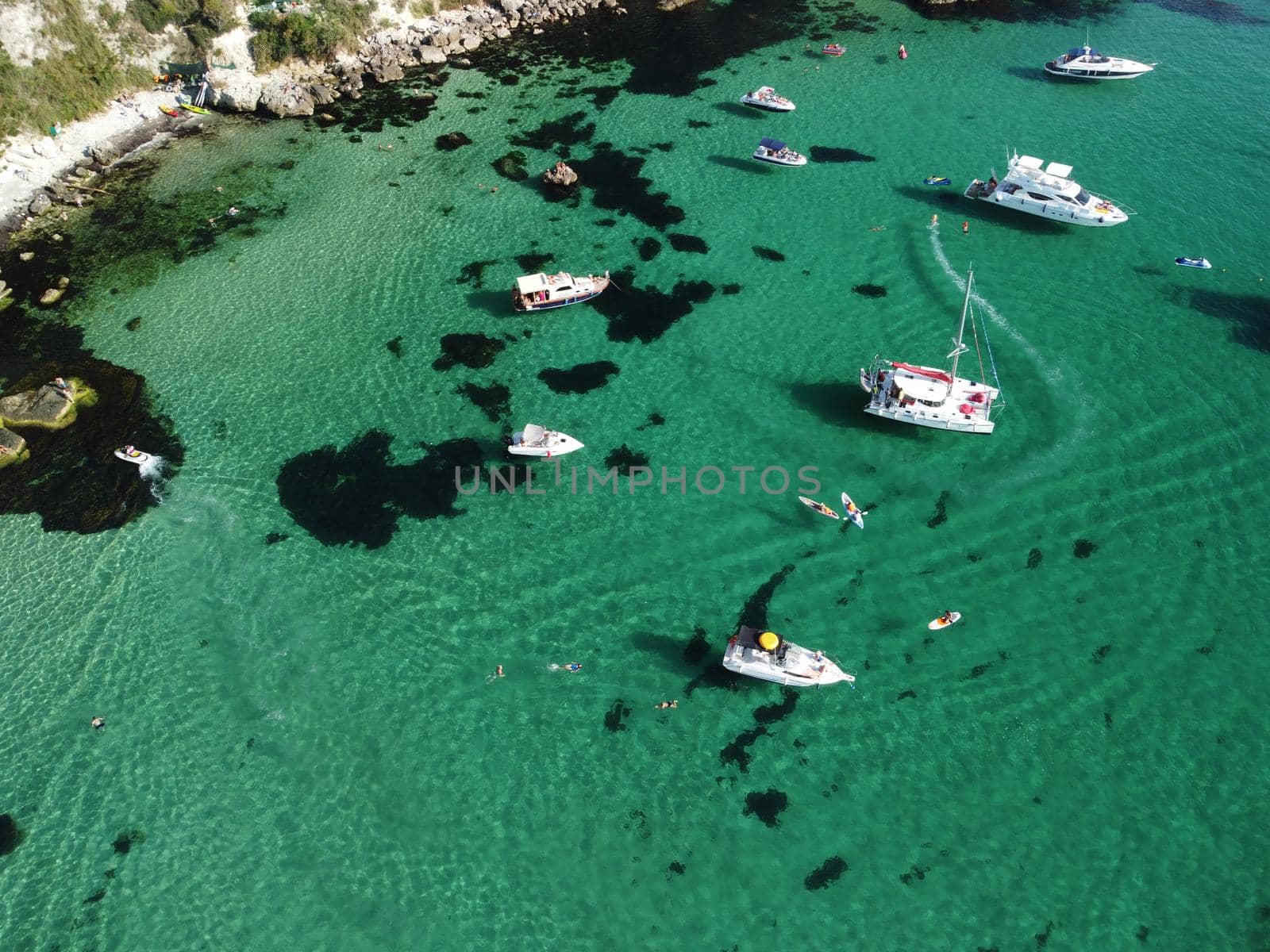 Sea landscape with rocky coastline on sunset time with cloudy sky. Yachts in the Sea on a background of rocky shores. The concept of perfect place for summer travel and rest.