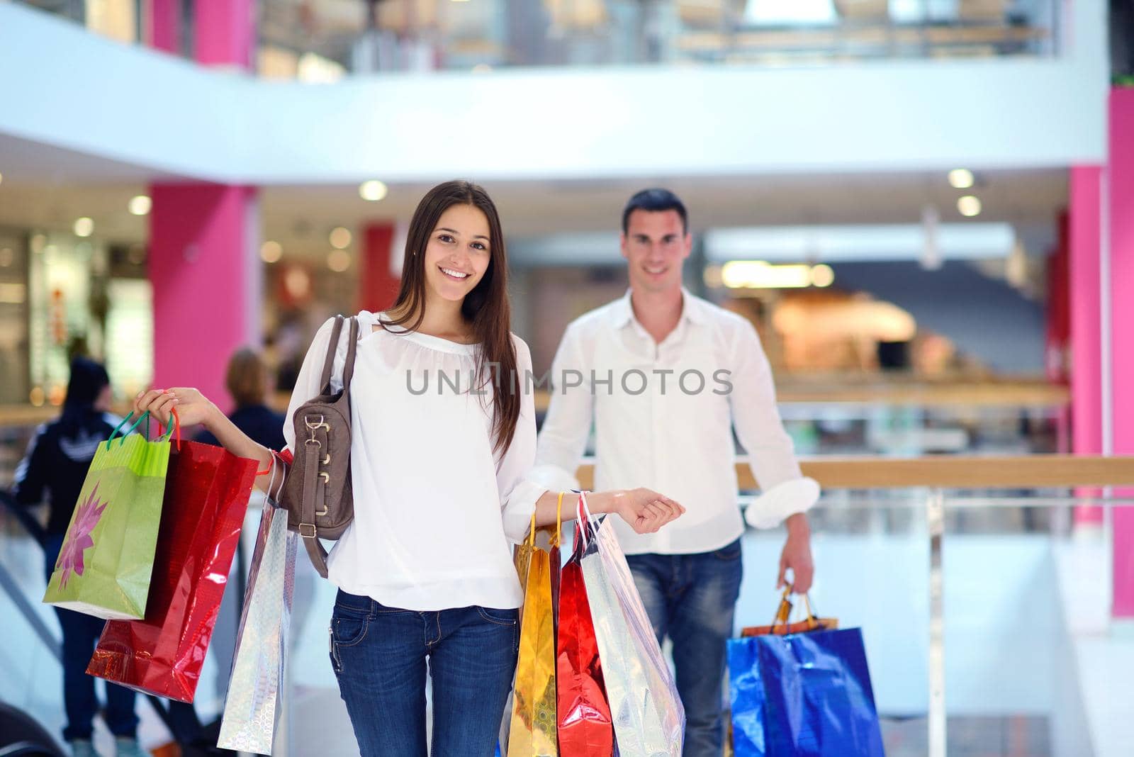 happy young couple with bags in shopping centre mall