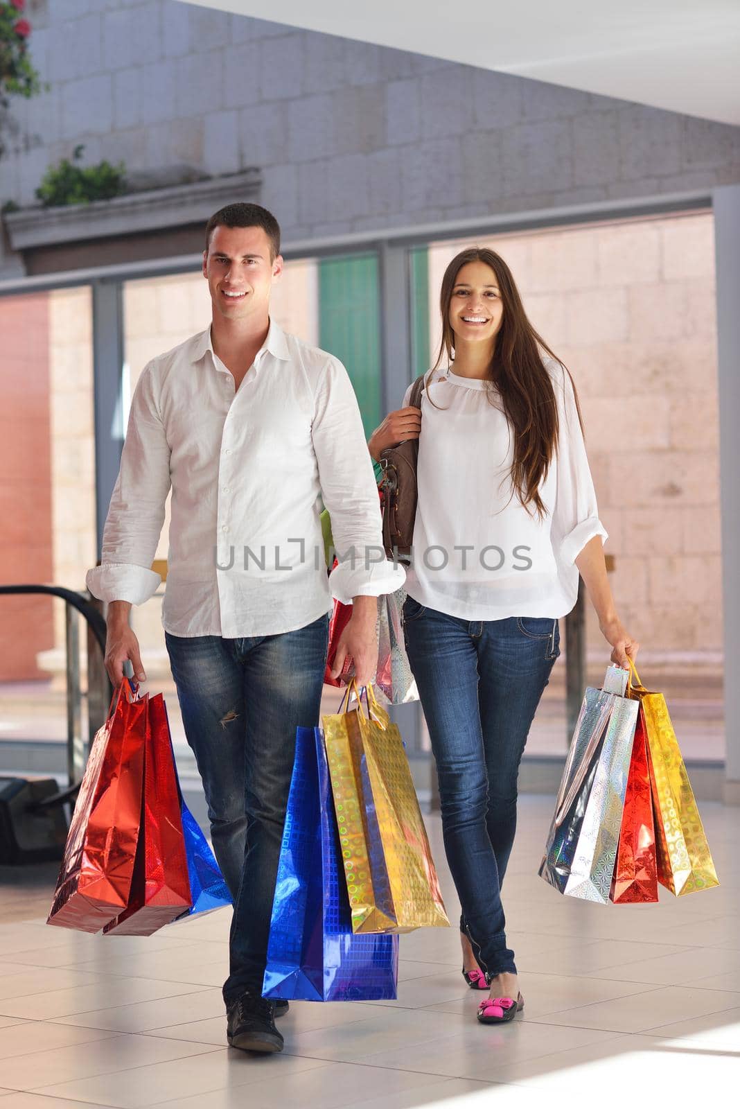 happy young couple with bags in shopping centre mall