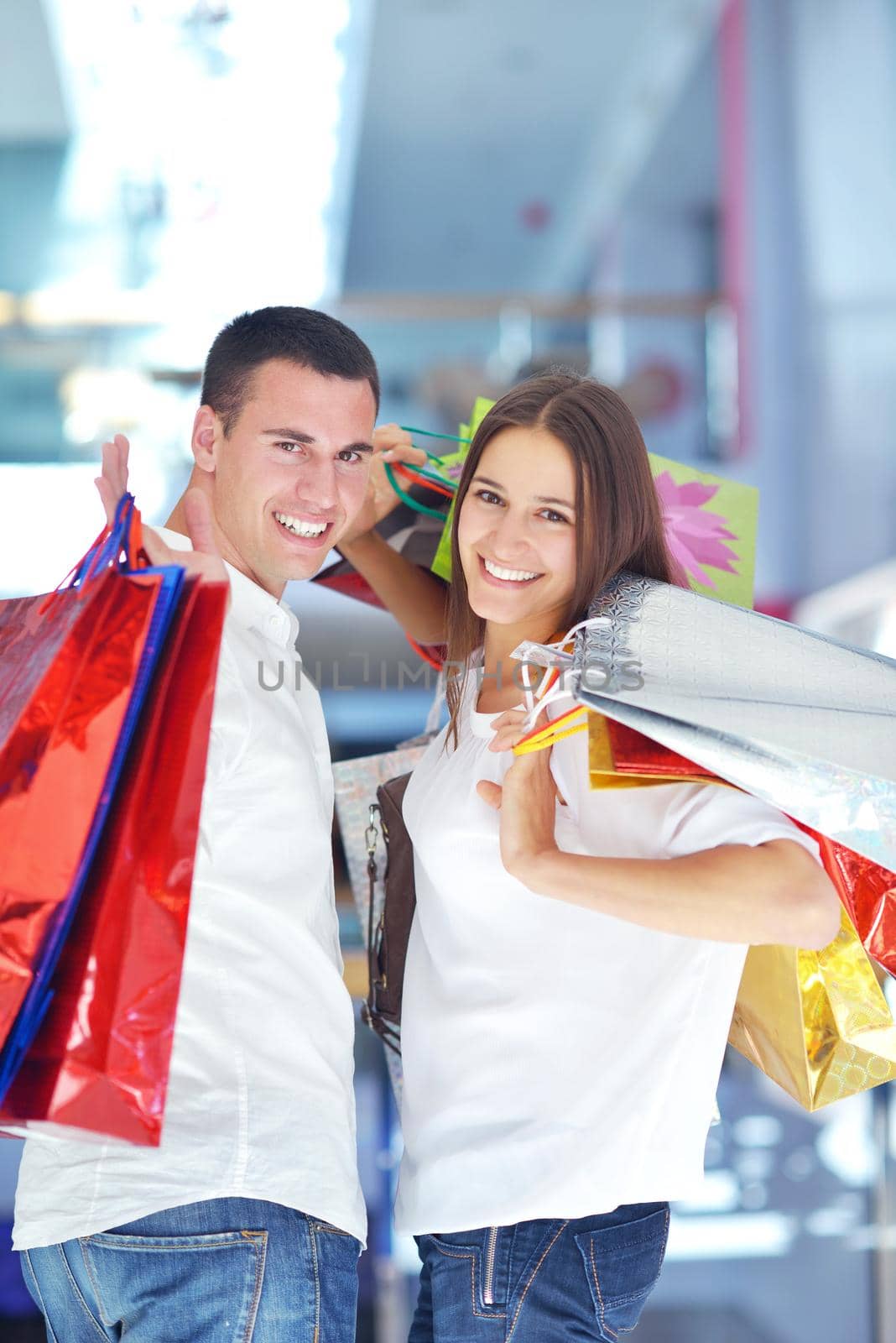 happy young couple with bags in shopping centre mall