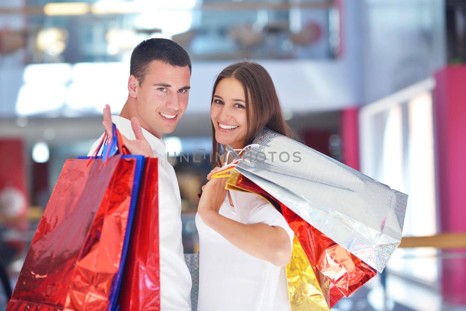 happy young couple with bags in shopping centre mall