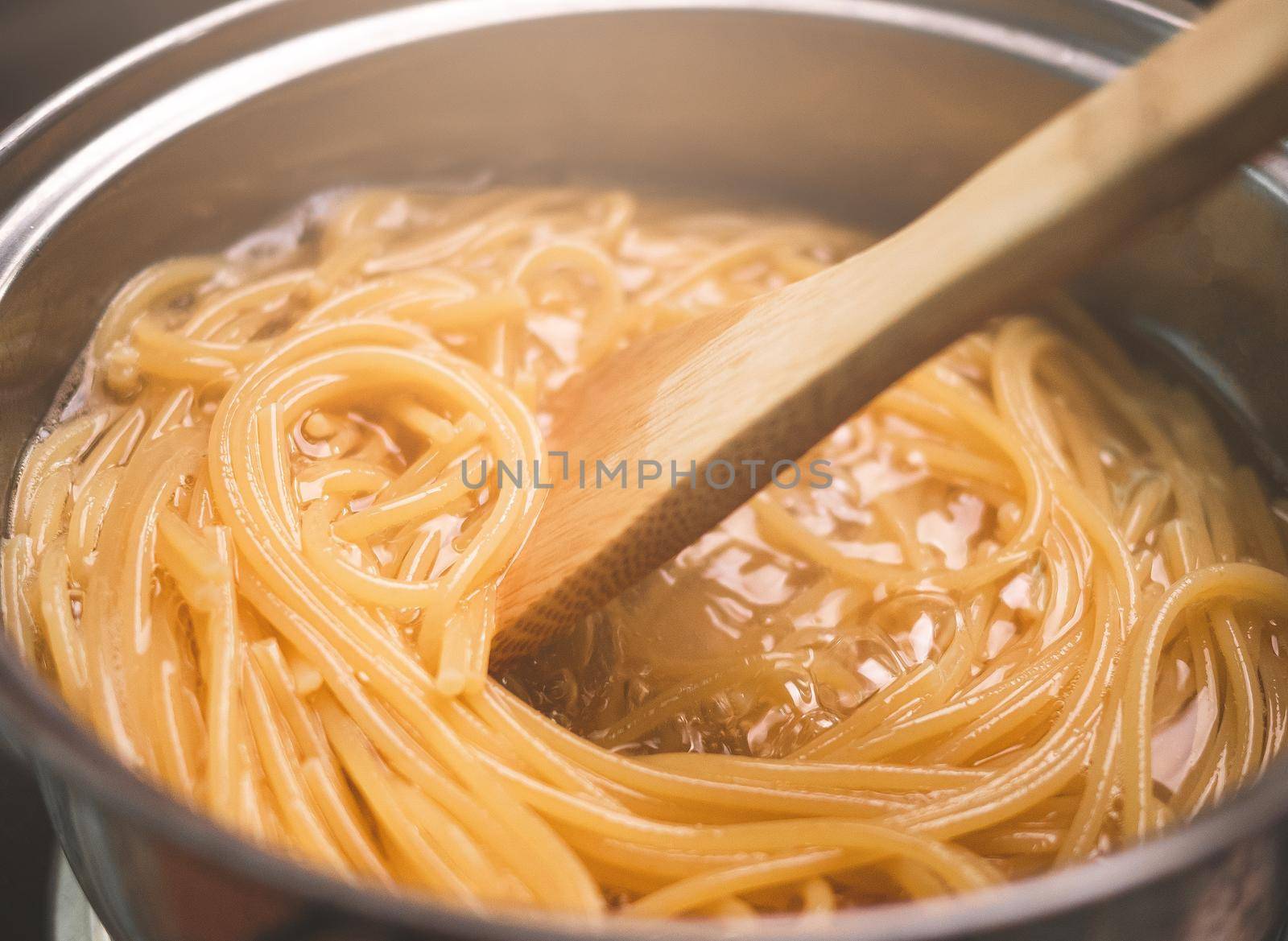 Raw spaghetti is being cooked in boiling water in a kitchen pot. Healthy Italian Food and Cooking concepts.