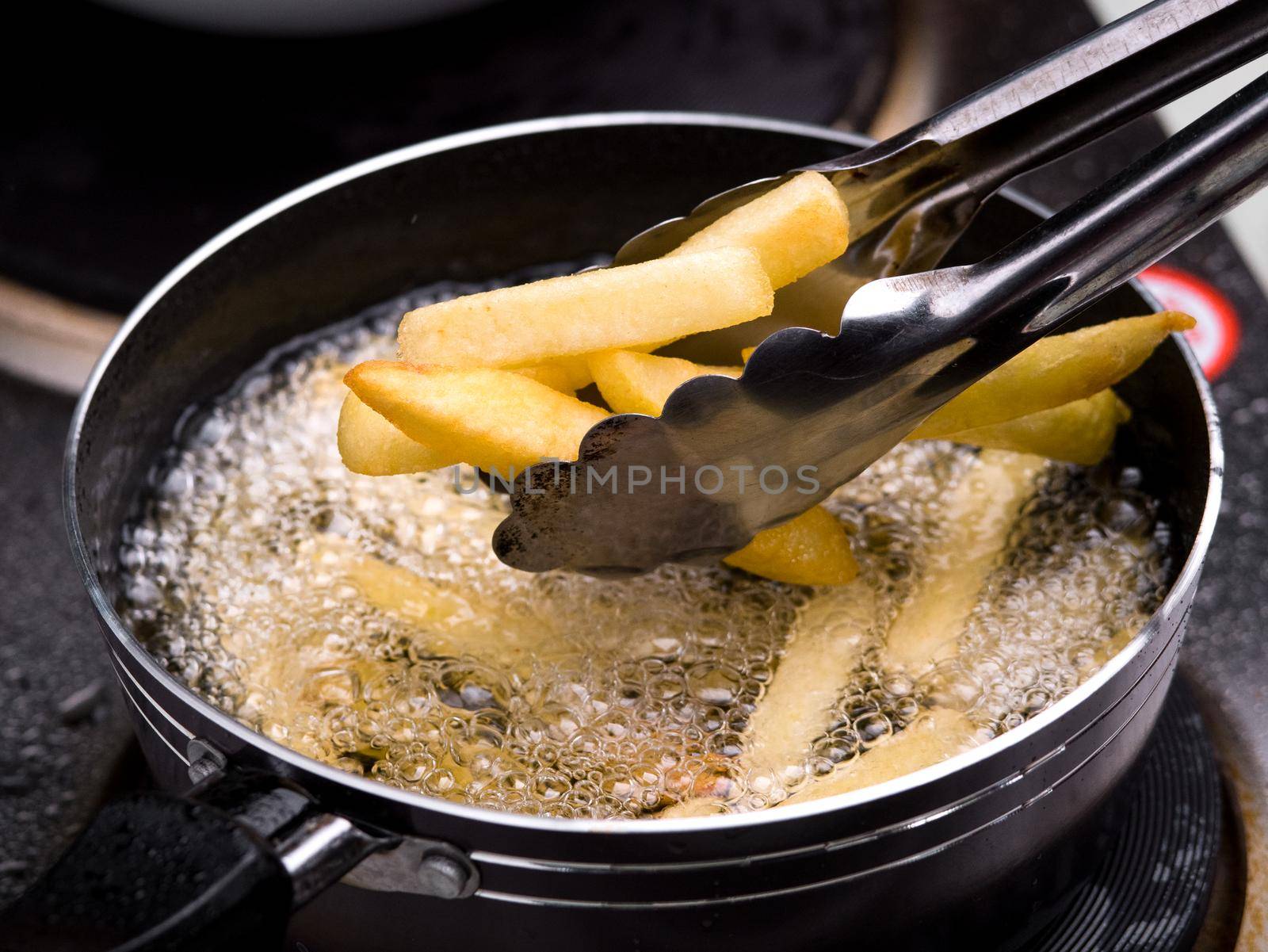 Close up of Frying french fries in the fryer in hot oil on the electric stove in the kitchen. Making homemade french fries.