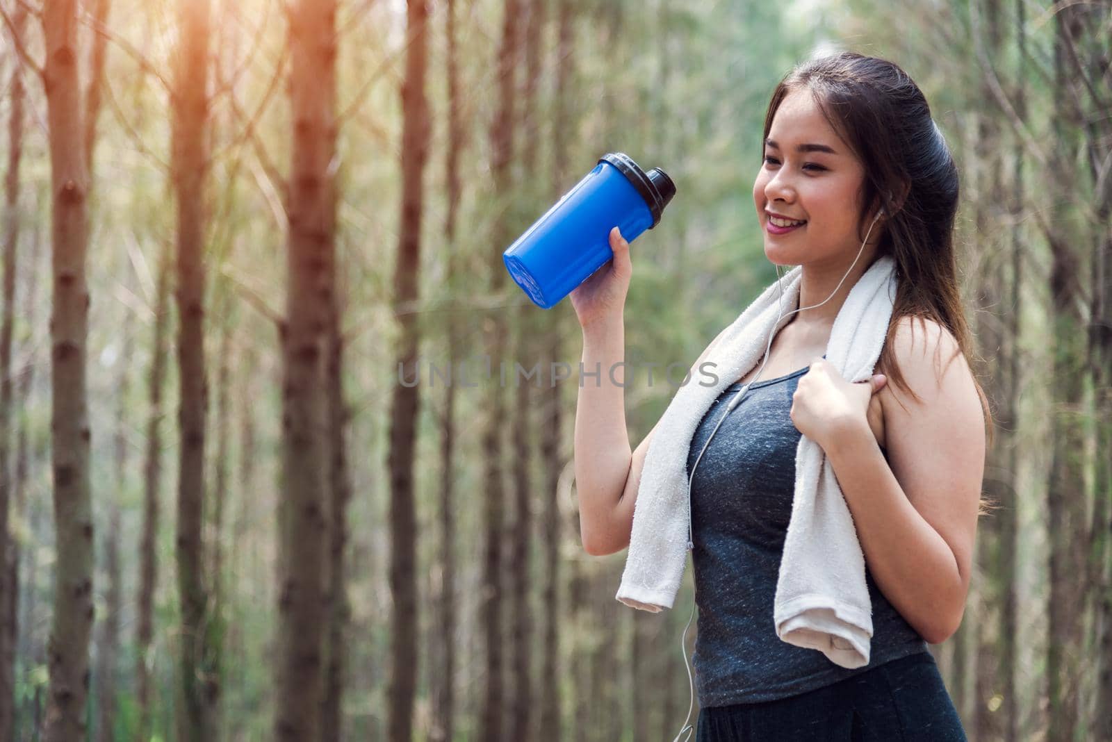 Beautiful sport young woman girl lifestyle exercise healthy drinking water after running workout in forest nature park with copy space