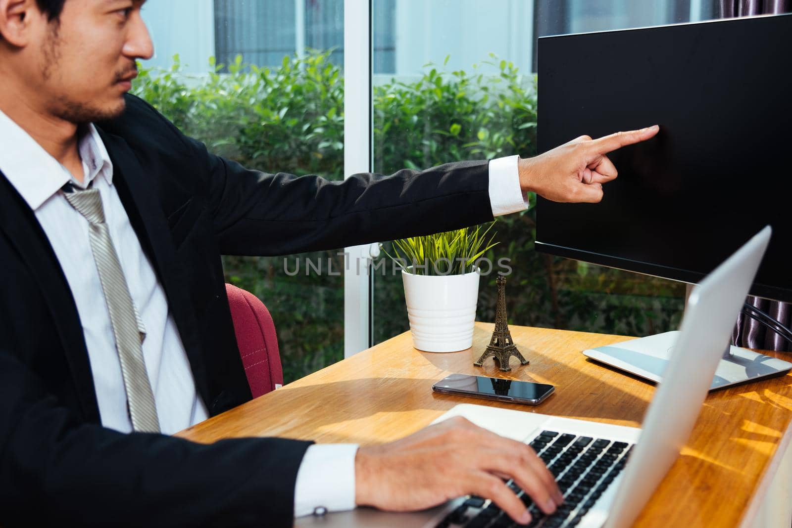 Business man using laptop computer on desk point hand to PC monitor