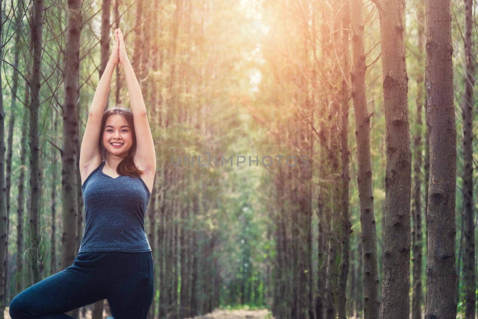 Beautiful young woman relaxation standing fitness exercise yoga in morning at forest tree nature park