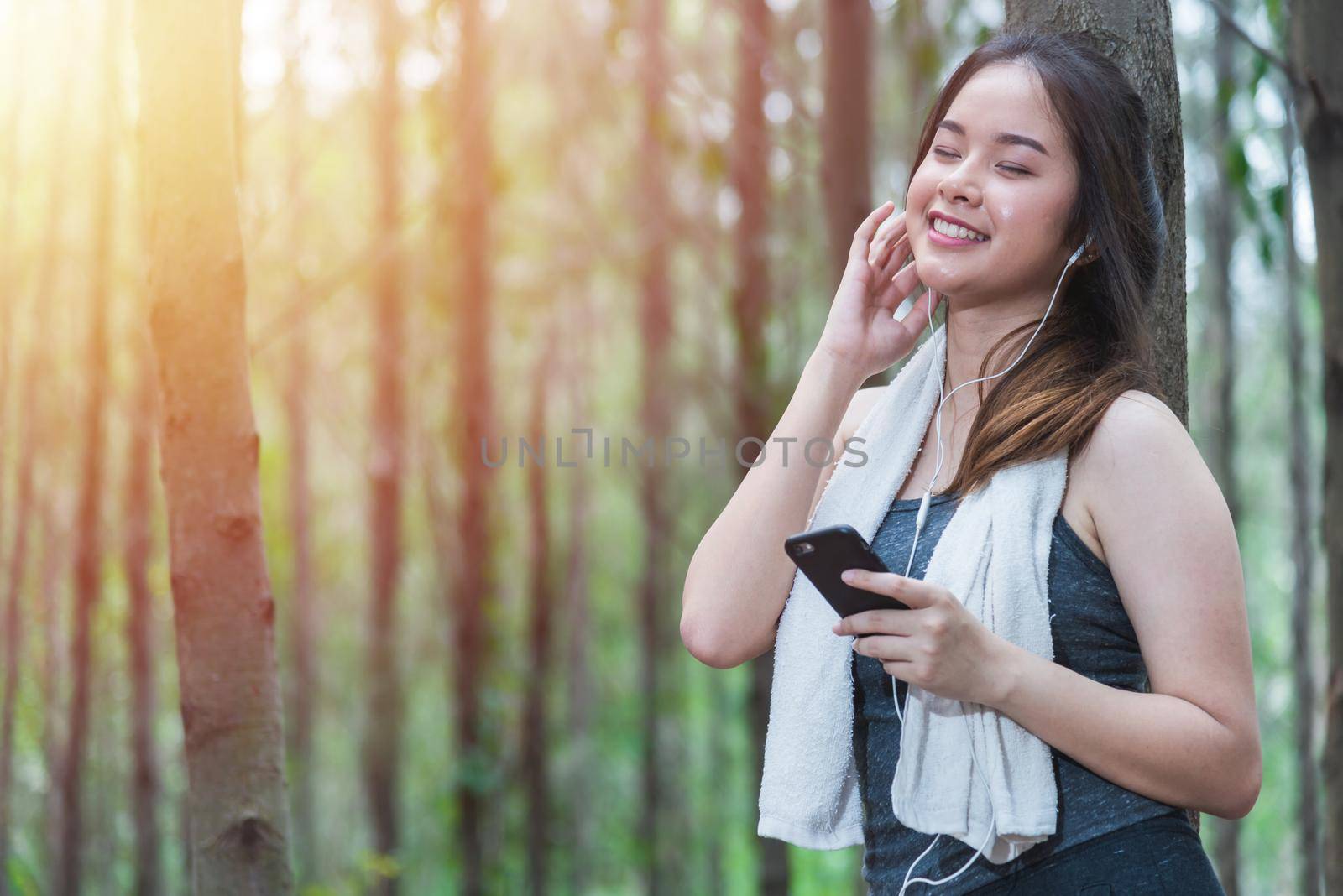 Young sport woman lifestyle using smart phone after running at forest park copy space