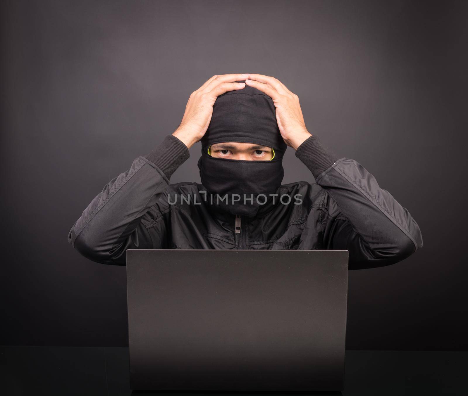 Computer hacker dizziness or headache - Male thief stealing data from laptop computer on black background