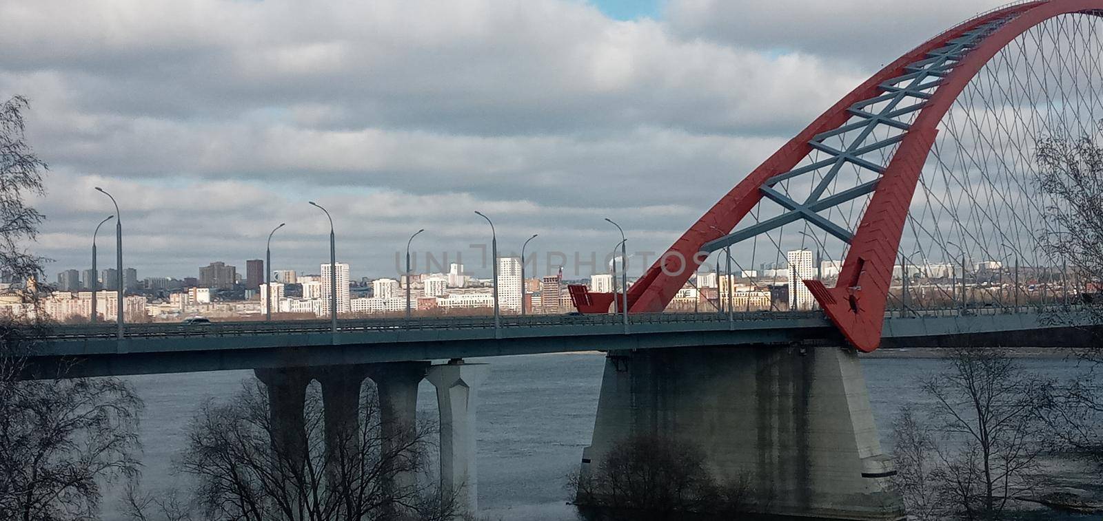 Red arch of the cable-stayed suspension bridge over the wide Ob River. Novosibirsk, Russia. Red suspension bridge over the Ob River. Bugrinsky bridge over the Ob River.