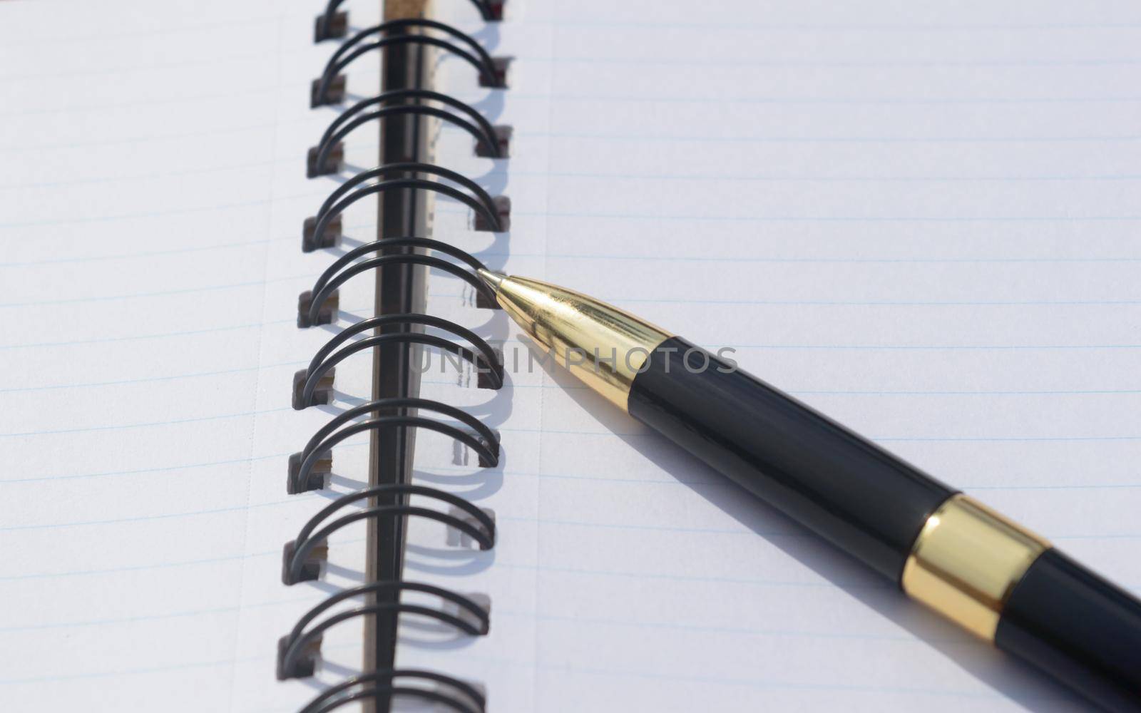pen placed over open spiral notebook or personal organizer. Business Education background.