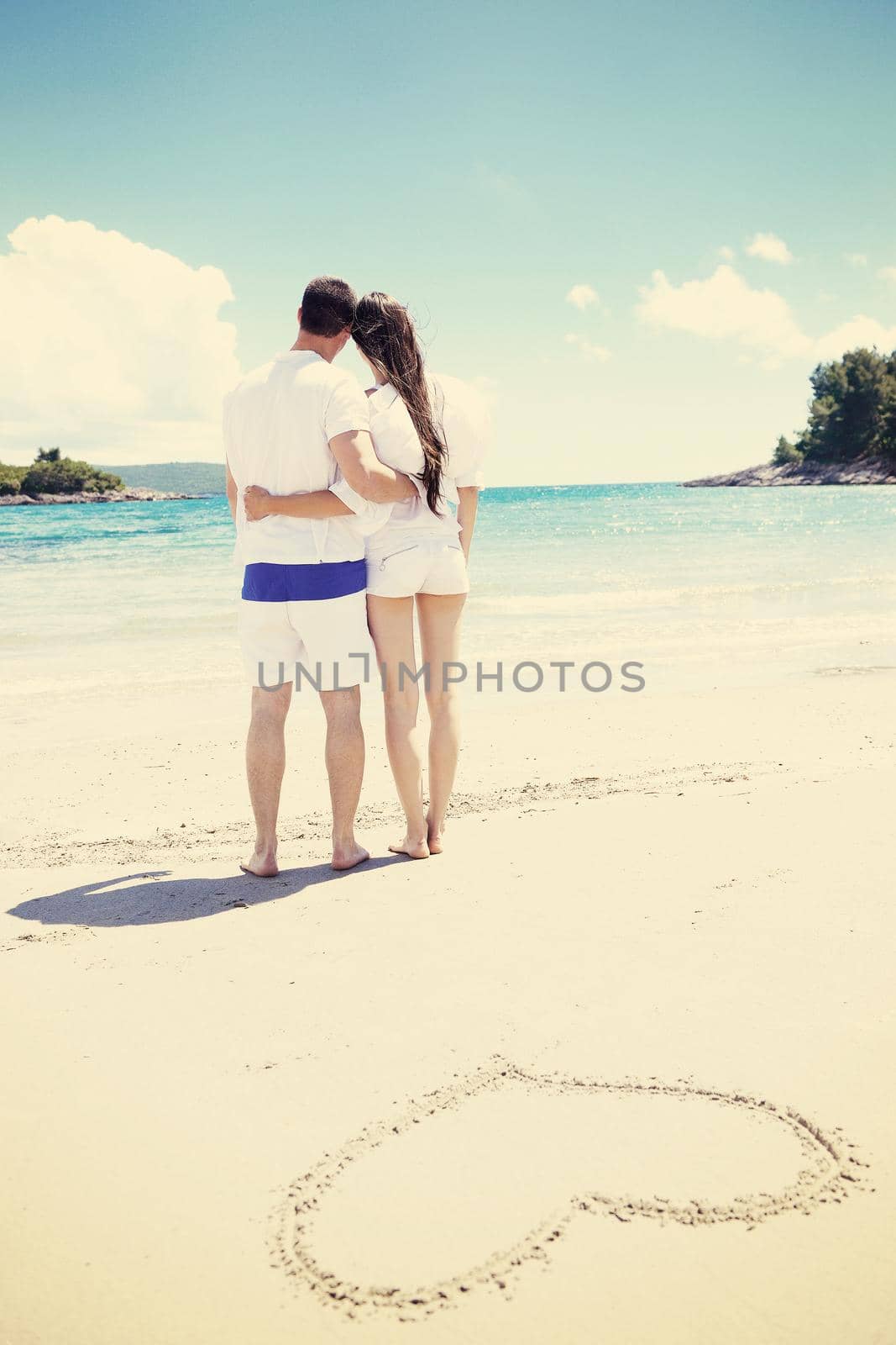 romantic  couple in love  have fun on the beach with heart drawing on sand by dotshock