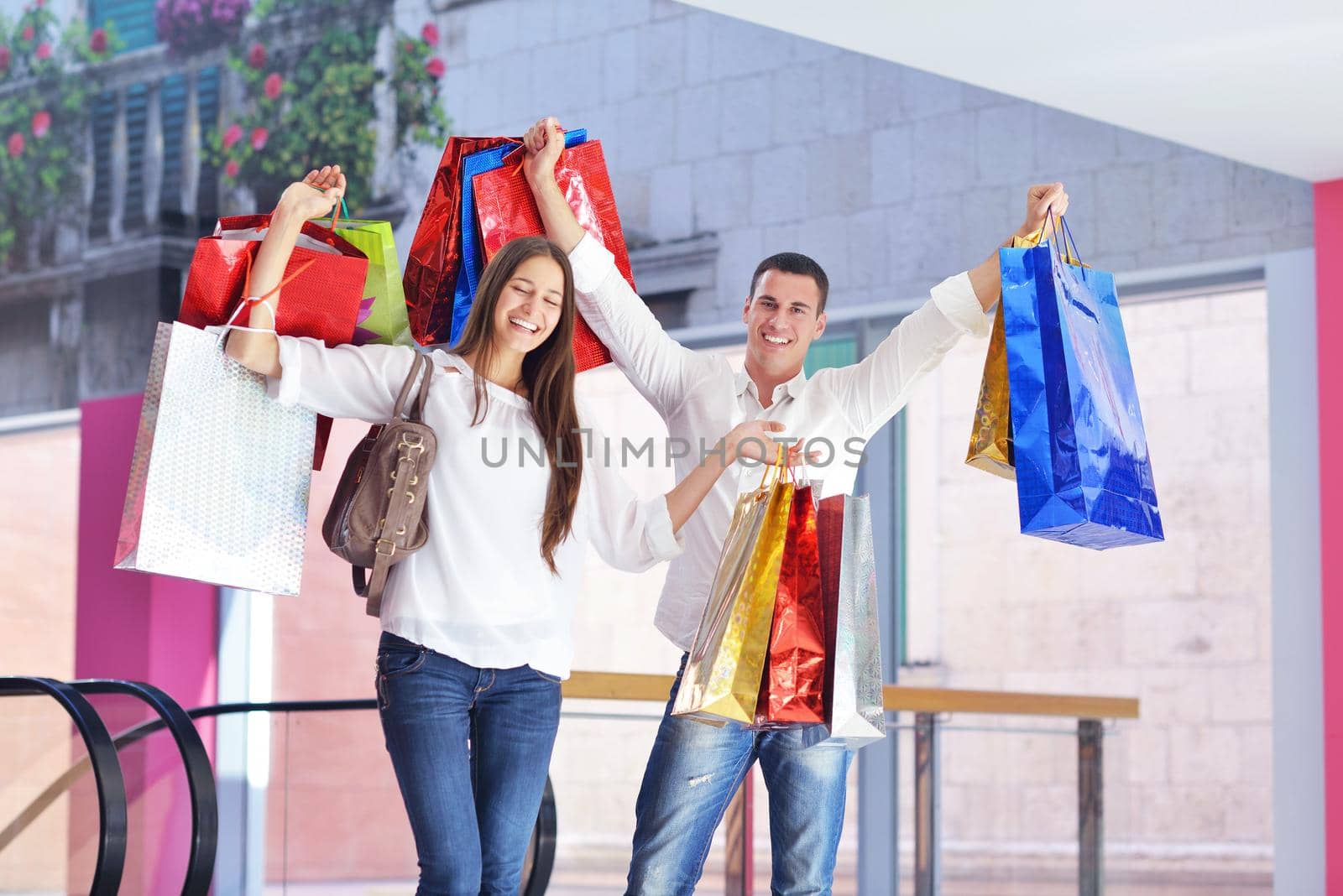 happy young couple with bags in shopping centre mall