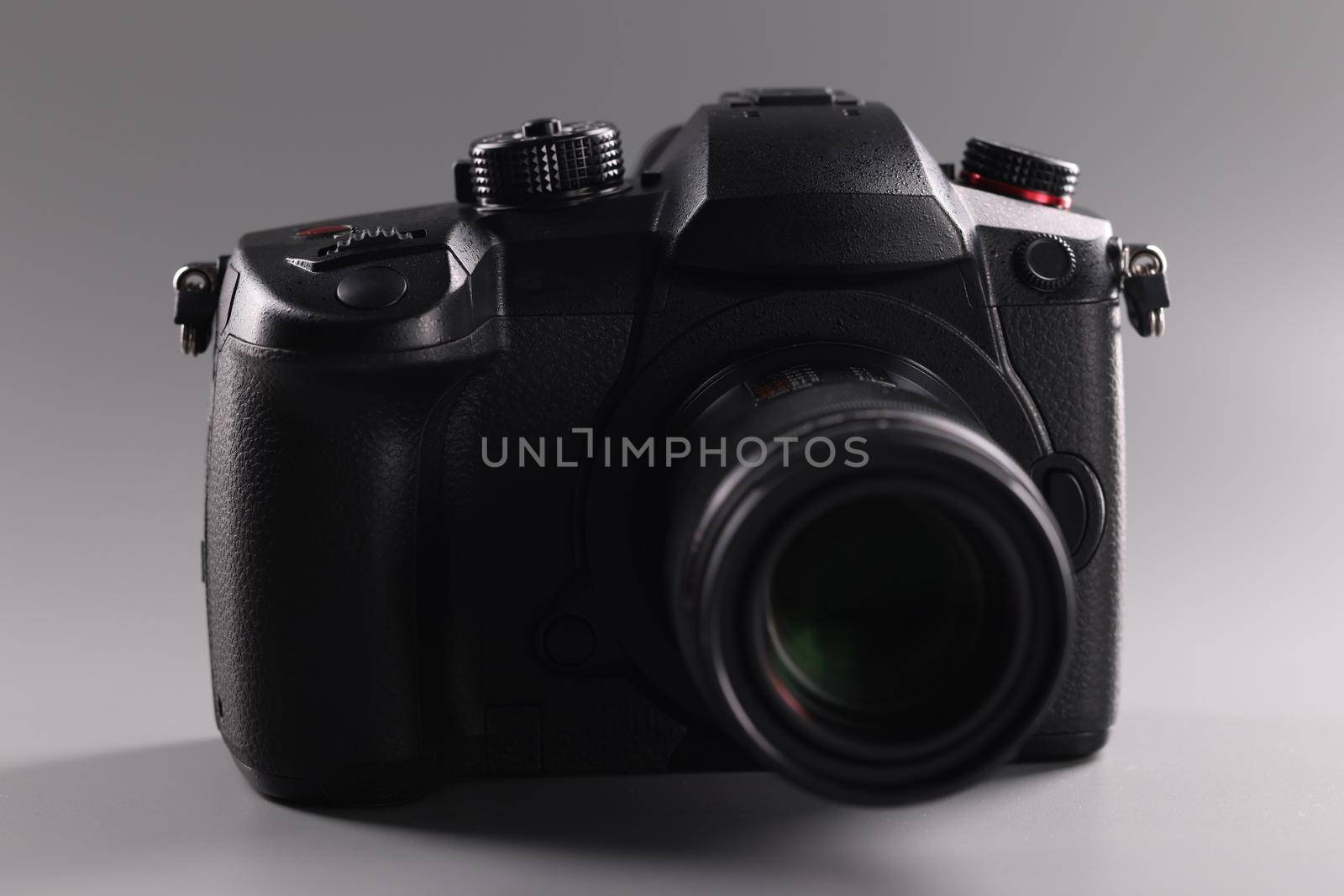 Closeup of black professional camera on gray background. Sale of photographic equipment concept