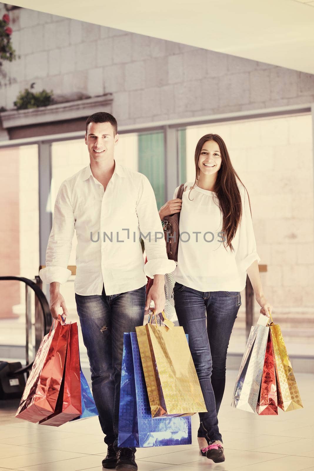 happy young couple with bags in shopping centre mall