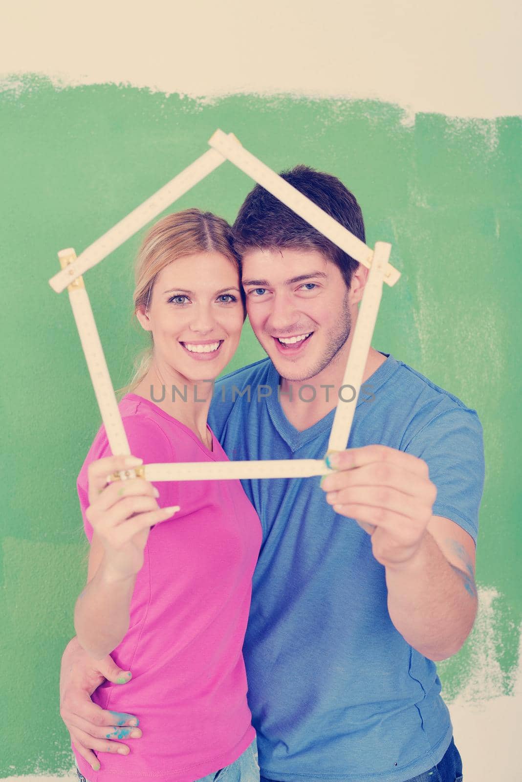 happy young couple paint in green and blue color white wall of their new home