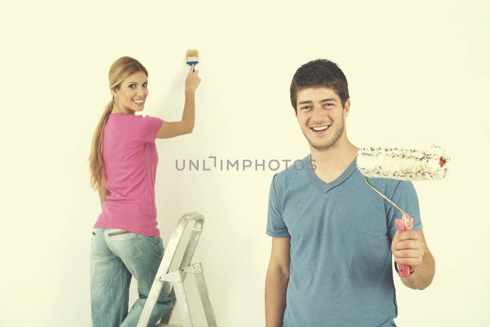 happy young couple paint in green and blue color white wall of their new home