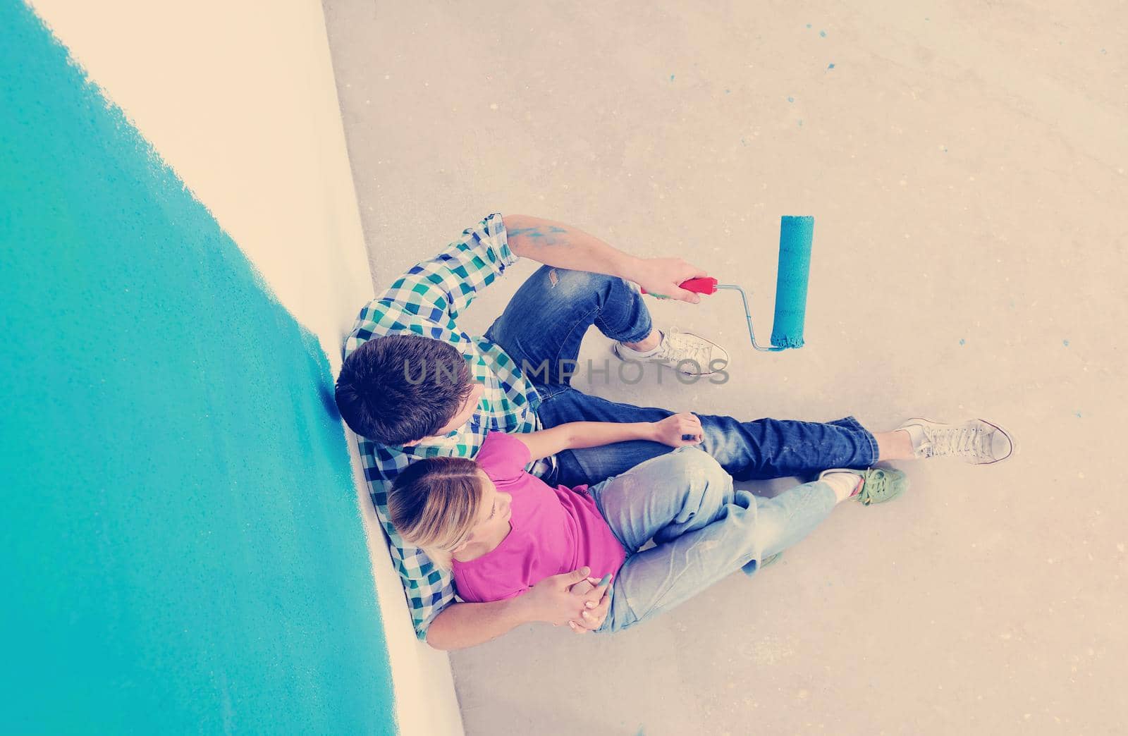 happy young couple relax after painting white wall in green and blue color in their new home