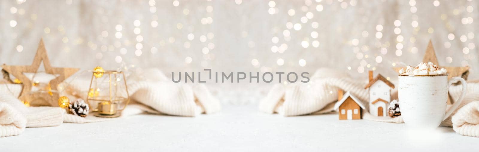 Details of Still life, cup of coffee with marshmallows, wooden decor, candle, Christmas lights with sweater on white background, home decor in cozy house. Banner for Winter weekend concept.