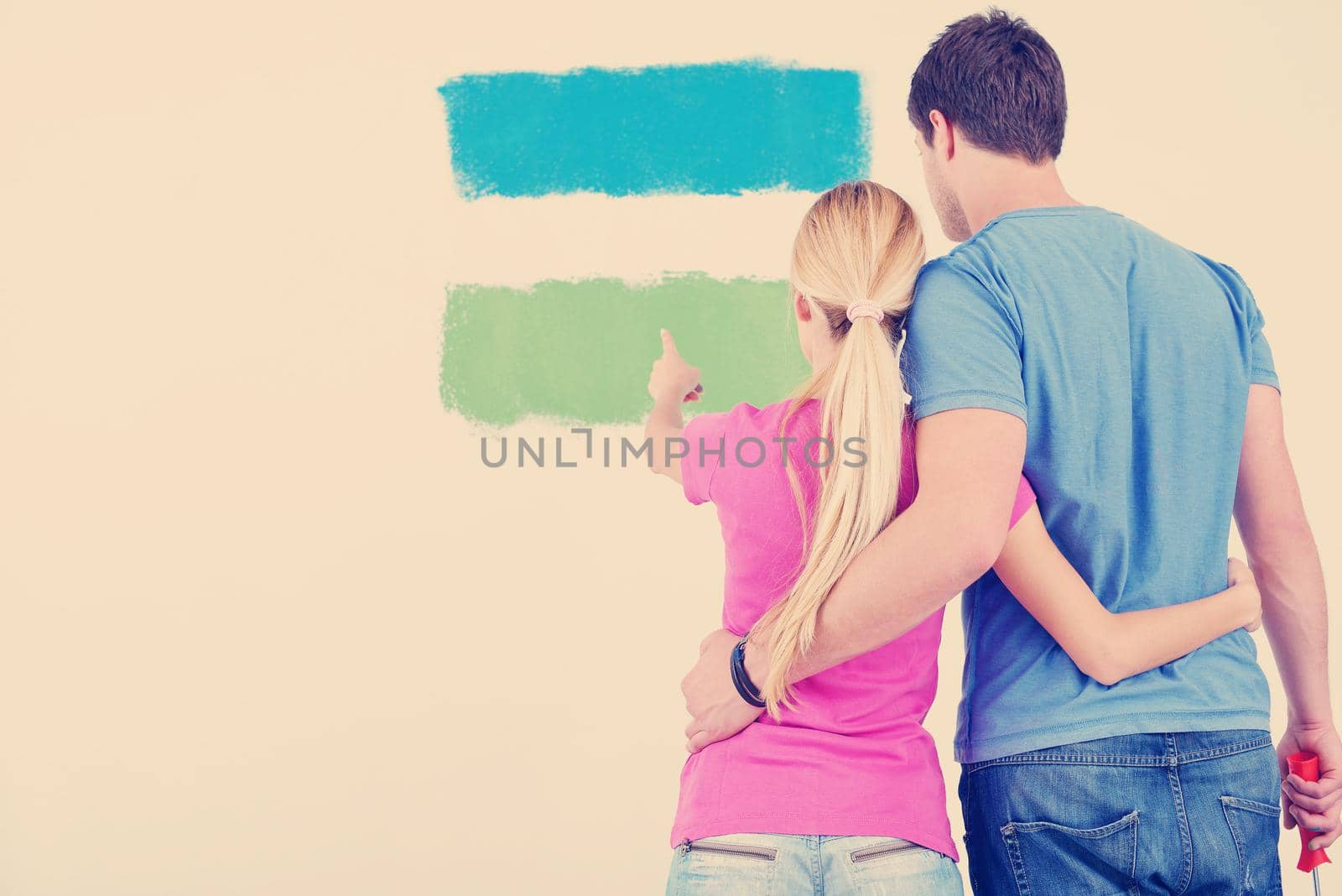 happy young couple paint in green and blue color white wall of their new home