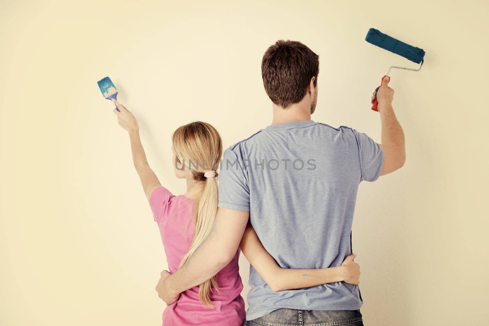 happy young couple paint in green and blue color white wall of their new home