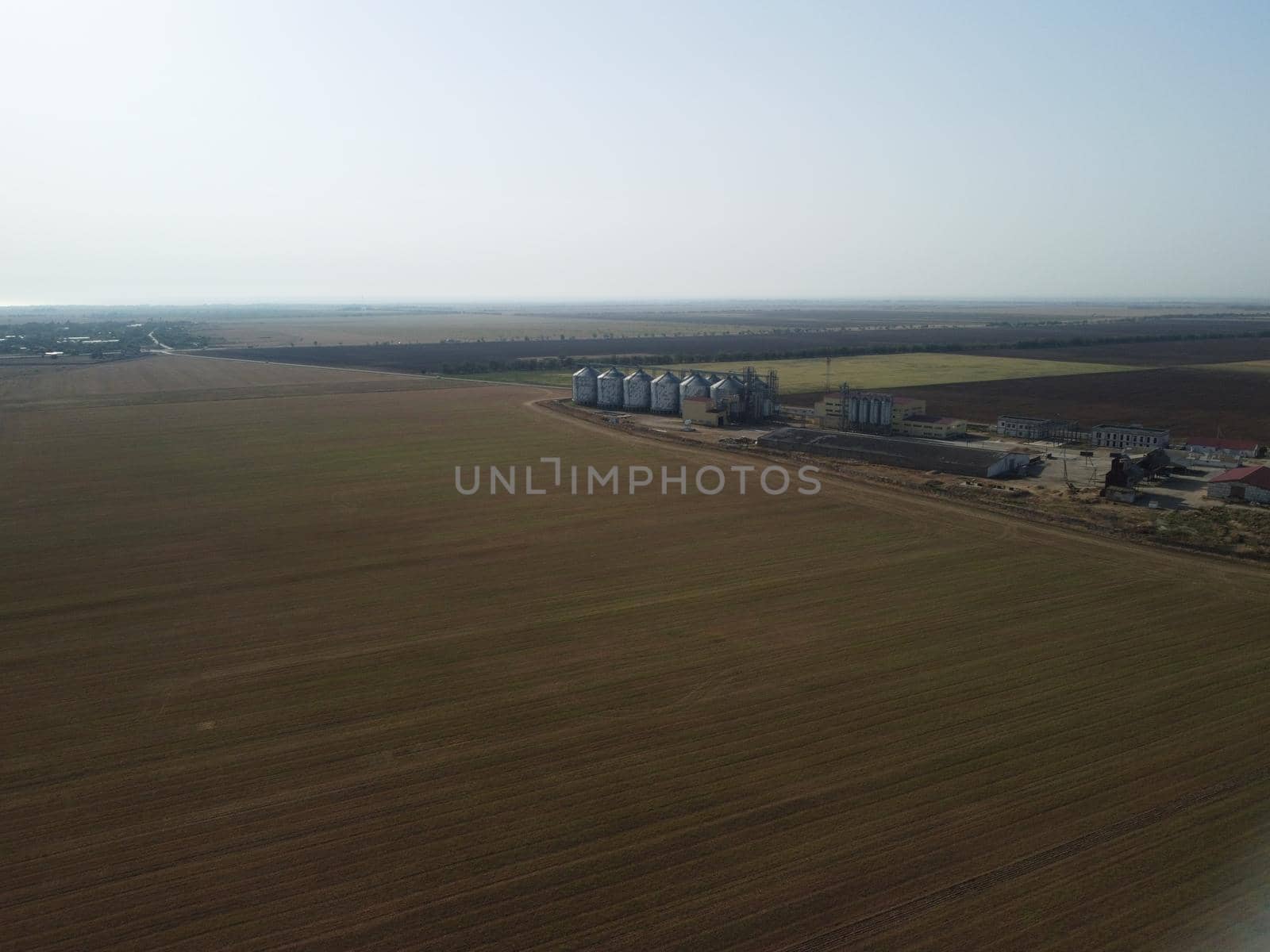 Grain elevator. Metal grain elevator in agricultural zone. Agriculture storage for harvest. Grain elevators on green nature background. Exterior of agricultural factory