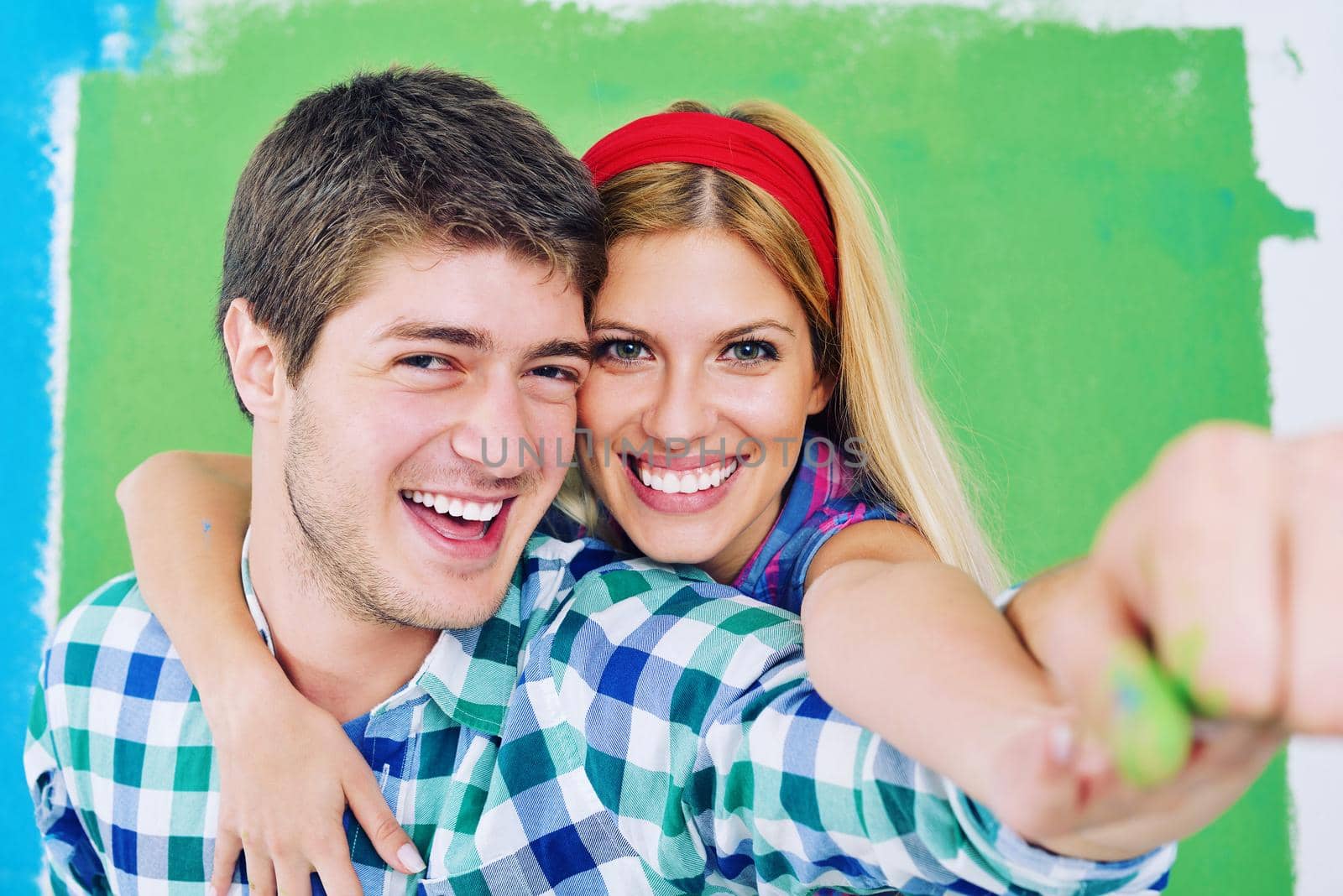 happy young couple paint in green and blue color white wall of their new home